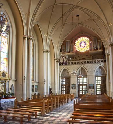 Zdjęcie nr 85: Kościół z cegły i kamienia. Na rzucie krzyża łacińskiego, jednonawowy z wciągniętymi do wnętrza przyporami. Prezbiterium krótkie, zamknięte pięcioma bokami ośmioboku. Korpus jednonawowy, czteroprzęsłowy, po bokach z płytkimi wnękami-kaplicami pomiędzy przyporami, poprzedzony od zach. przedsionkiem. Do pierwszego przęsła dostawione dwie symetryczne, trójboczne kaplice, nad nimi dwie czworoboczne wieże. Zakrystia przy prezbiterium na osi kościoła. Artykulacja ścian wnętrza za pomocą filarów opiętych półkolumnami z kapitelami z motywów liści. Między filarami rozpięte ostrołukowe arkady tworzące płytkie wnęki. Pierwsze przęsło wyróżnione przy pomocy masywnych filarów, ujętych niemal pełnoplastycznymi kolumnami. Okna ostrołukowe, dwudzielne z maswerkami, wsparte na gzymsach. Sklepienia krzyżowo-żebrowe na zaostrzonych gurtach. Kaplice artykułowane analogicznie do nawy kościoła, ze sklepieniami gwiaździstymi. Przedsionek otwiera się do kościoła trzema portalami ostrołukowymi opiętymi kolumnami. W polach archiwolt płaskorzeźby: Boże Narodzenie, Ukrzyżowanie, Wniebowstąpienie (K. Ceptowski).  W prezbiterium, na osi kościoła prostokątny otwór drzwiowy prowadzący do zakrystii. Chór muzyczny umieszczony nad kruchtą kościoła, na rzucie prostokąta, z kamienną balustradą maswerkową. Fasada kamienna, trójosiowa, zamknięta trójkątnie, flankowana lizenami przechodzącymi w ażurowe wieżyczki-latarnie, na rzucie kwadratu. Wieżyczki zwieńczone gzymsem i balustradą arkadową, hełmy ostrosłupowy zakończony iglicą. W dolnej części trzy filarowe arkady ostrołukowe, otwierające się do kruchty, sklepienie kruchty krzyżowo-żebrowe. Nad arkadami wejściowymi trzy tonda: litery IHS, Oko Opatrzności i splecione litery imienia Maria. Pośrodku na osi kościoła duża rozeta z maswerkiem, profilowana, otoczona pierścieniem wypełnionym stylizowanym ornamentem roślinnym. Ponad arkadami pełnoplastyczne figury czterech ewangelistów ustawionych na konsolach z rzeźbionymi atrybutami (F. Kuhn). Po bokach rozety prostokątne płyciny z traczami herbowymi Potockich i Branickich. U góry, na osi fasady figura Archanioła Michała. Elewacje na kamiennym cokole, z gzymsem kapnikowym, opięte prostokątnymi przyporami zwieńczonymi kamiennymi nakrywami. W górnej części kamienny fryz arkadkowy. Nad nim gzyms koronujący podtrzymujący ażurową, arkadową balustradę. Przy prezbiterium kaplice zamknięte trójbocznie, prezbiterium zamknięte pięciobocznie. Zakrystia na osi prezbiterium, na rzucie prostokąta, zwieńczona sygnaturką i ceglanym kominem. Po bokach prostokątne aneksy, południowy aneks - trzy okna ostrołukowe w kamiennej opasce, w środkowym przedstawienie Ukrzyżowanego Chrystusa. W północnym aneksie pojedyncze analogiczne okno. Okna ostrołukowe w profilowanych kamiennych opaskach, pomiędzy nimi a gzymsem koronującym mniejsze ostrołukowe w uskokowych arkadach. Nad kaplicami bocznymi dwie symetryczne wieże na rzucie kwadratu, w połowie wysokości kamienny gzyms z fryzem arkadkowym. Okna ostrołukowe w kamiennej opasce. Całość zwieńczona ślepym fryzem arkadkowym, wyżej gzyms dźwigający ażurową arkadkową balustradę. Hełmy ostrosłupowe, miedziane. Zakrystia na rzucie prostokąta, nakryta sklepieniem kolebkowym zaostrzonym i krzyżowym z lunetami , oddzielone gurtem. Portale od wschodu i zachodu prostokątne zamknięte łukiem ostrym. Okna ostrołukowe.