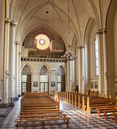 Zdjęcie nr 87: Kościół z cegły i kamienia. Na rzucie krzyża łacińskiego, jednonawowy z wciągniętymi do wnętrza przyporami. Prezbiterium krótkie, zamknięte pięcioma bokami ośmioboku. Korpus jednonawowy, czteroprzęsłowy, po bokach z płytkimi wnękami-kaplicami pomiędzy przyporami, poprzedzony od zach. przedsionkiem. Do pierwszego przęsła dostawione dwie symetryczne, trójboczne kaplice, nad nimi dwie czworoboczne wieże. Zakrystia przy prezbiterium na osi kościoła. Artykulacja ścian wnętrza za pomocą filarów opiętych półkolumnami z kapitelami z motywów liści. Między filarami rozpięte ostrołukowe arkady tworzące płytkie wnęki. Pierwsze przęsło wyróżnione przy pomocy masywnych filarów, ujętych niemal pełnoplastycznymi kolumnami. Okna ostrołukowe, dwudzielne z maswerkami, wsparte na gzymsach. Sklepienia krzyżowo-żebrowe na zaostrzonych gurtach. Kaplice artykułowane analogicznie do nawy kościoła, ze sklepieniami gwiaździstymi. Przedsionek otwiera się do kościoła trzema portalami ostrołukowymi opiętymi kolumnami. W polach archiwolt płaskorzeźby: Boże Narodzenie, Ukrzyżowanie, Wniebowstąpienie (K. Ceptowski).  W prezbiterium, na osi kościoła prostokątny otwór drzwiowy prowadzący do zakrystii. Chór muzyczny umieszczony nad kruchtą kościoła, na rzucie prostokąta, z kamienną balustradą maswerkową. Fasada kamienna, trójosiowa, zamknięta trójkątnie, flankowana lizenami przechodzącymi w ażurowe wieżyczki-latarnie, na rzucie kwadratu. Wieżyczki zwieńczone gzymsem i balustradą arkadową, hełmy ostrosłupowy zakończony iglicą. W dolnej części trzy filarowe arkady ostrołukowe, otwierające się do kruchty, sklepienie kruchty krzyżowo-żebrowe. Nad arkadami wejściowymi trzy tonda: litery IHS, Oko Opatrzności i splecione litery imienia Maria. Pośrodku na osi kościoła duża rozeta z maswerkiem, profilowana, otoczona pierścieniem wypełnionym stylizowanym ornamentem roślinnym. Ponad arkadami pełnoplastyczne figury czterech ewangelistów ustawionych na konsolach z rzeźbionymi atrybutami (F. Kuhn). Po bokach rozety prostokątne płyciny z traczami herbowymi Potockich i Branickich. U góry, na osi fasady figura Archanioła Michała. Elewacje na kamiennym cokole, z gzymsem kapnikowym, opięte prostokątnymi przyporami zwieńczonymi kamiennymi nakrywami. W górnej części kamienny fryz arkadkowy. Nad nim gzyms koronujący podtrzymujący ażurową, arkadową balustradę. Przy prezbiterium kaplice zamknięte trójbocznie, prezbiterium zamknięte pięciobocznie. Zakrystia na osi prezbiterium, na rzucie prostokąta, zwieńczona sygnaturką i ceglanym kominem. Po bokach prostokątne aneksy, południowy aneks - trzy okna ostrołukowe w kamiennej opasce, w środkowym przedstawienie Ukrzyżowanego Chrystusa. W północnym aneksie pojedyncze analogiczne okno. Okna ostrołukowe w profilowanych kamiennych opaskach, pomiędzy nimi a gzymsem koronującym mniejsze ostrołukowe w uskokowych arkadach. Nad kaplicami bocznymi dwie symetryczne wieże na rzucie kwadratu, w połowie wysokości kamienny gzyms z fryzem arkadkowym. Okna ostrołukowe w kamiennej opasce. Całość zwieńczona ślepym fryzem arkadkowym, wyżej gzyms dźwigający ażurową arkadkową balustradę. Hełmy ostrosłupowe, miedziane. Zakrystia na rzucie prostokąta, nakryta sklepieniem kolebkowym zaostrzonym i krzyżowym z lunetami , oddzielone gurtem. Portale od wschodu i zachodu prostokątne zamknięte łukiem ostrym. Okna ostrołukowe.