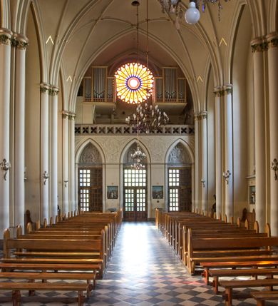 Zdjęcie nr 82: Kościół z cegły i kamienia. Na rzucie krzyża łacińskiego, jednonawowy z wciągniętymi do wnętrza przyporami. Prezbiterium krótkie, zamknięte pięcioma bokami ośmioboku. Korpus jednonawowy, czteroprzęsłowy, po bokach z płytkimi wnękami-kaplicami pomiędzy przyporami, poprzedzony od zach. przedsionkiem. Do pierwszego przęsła dostawione dwie symetryczne, trójboczne kaplice, nad nimi dwie czworoboczne wieże. Zakrystia przy prezbiterium na osi kościoła. Artykulacja ścian wnętrza za pomocą filarów opiętych półkolumnami z kapitelami z motywów liści. Między filarami rozpięte ostrołukowe arkady tworzące płytkie wnęki. Pierwsze przęsło wyróżnione przy pomocy masywnych filarów, ujętych niemal pełnoplastycznymi kolumnami. Okna ostrołukowe, dwudzielne z maswerkami, wsparte na gzymsach. Sklepienia krzyżowo-żebrowe na zaostrzonych gurtach. Kaplice artykułowane analogicznie do nawy kościoła, ze sklepieniami gwiaździstymi. Przedsionek otwiera się do kościoła trzema portalami ostrołukowymi opiętymi kolumnami. W polach archiwolt płaskorzeźby: Boże Narodzenie, Ukrzyżowanie, Wniebowstąpienie (K. Ceptowski).  W prezbiterium, na osi kościoła prostokątny otwór drzwiowy prowadzący do zakrystii. Chór muzyczny umieszczony nad kruchtą kościoła, na rzucie prostokąta, z kamienną balustradą maswerkową. Fasada kamienna, trójosiowa, zamknięta trójkątnie, flankowana lizenami przechodzącymi w ażurowe wieżyczki-latarnie, na rzucie kwadratu. Wieżyczki zwieńczone gzymsem i balustradą arkadową, hełmy ostrosłupowy zakończony iglicą. W dolnej części trzy filarowe arkady ostrołukowe, otwierające się do kruchty, sklepienie kruchty krzyżowo-żebrowe. Nad arkadami wejściowymi trzy tonda: litery IHS, Oko Opatrzności i splecione litery imienia Maria. Pośrodku na osi kościoła duża rozeta z maswerkiem, profilowana, otoczona pierścieniem wypełnionym stylizowanym ornamentem roślinnym. Ponad arkadami pełnoplastyczne figury czterech ewangelistów ustawionych na konsolach z rzeźbionymi atrybutami (F. Kuhn). Po bokach rozety prostokątne płyciny z traczami herbowymi Potockich i Branickich. U góry, na osi fasady figura Archanioła Michała. Elewacje na kamiennym cokole, z gzymsem kapnikowym, opięte prostokątnymi przyporami zwieńczonymi kamiennymi nakrywami. W górnej części kamienny fryz arkadkowy. Nad nim gzyms koronujący podtrzymujący ażurową, arkadową balustradę. Przy prezbiterium kaplice zamknięte trójbocznie, prezbiterium zamknięte pięciobocznie. Zakrystia na osi prezbiterium, na rzucie prostokąta, zwieńczona sygnaturką i ceglanym kominem. Po bokach prostokątne aneksy, południowy aneks - trzy okna ostrołukowe w kamiennej opasce, w środkowym przedstawienie Ukrzyżowanego Chrystusa. W północnym aneksie pojedyncze analogiczne okno. Okna ostrołukowe w profilowanych kamiennych opaskach, pomiędzy nimi a gzymsem koronującym mniejsze ostrołukowe w uskokowych arkadach. Nad kaplicami bocznymi dwie symetryczne wieże na rzucie kwadratu, w połowie wysokości kamienny gzyms z fryzem arkadkowym. Okna ostrołukowe w kamiennej opasce. Całość zwieńczona ślepym fryzem arkadkowym, wyżej gzyms dźwigający ażurową arkadkową balustradę. Hełmy ostrosłupowe, miedziane. Zakrystia na rzucie prostokąta, nakryta sklepieniem kolebkowym zaostrzonym i krzyżowym z lunetami , oddzielone gurtem. Portale od wschodu i zachodu prostokątne zamknięte łukiem ostrym. Okna ostrołukowe.