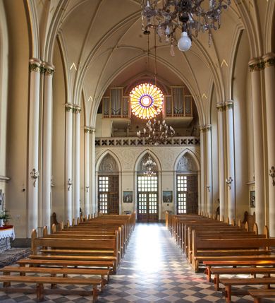 Zdjęcie nr 83: Kościół z cegły i kamienia. Na rzucie krzyża łacińskiego, jednonawowy z wciągniętymi do wnętrza przyporami. Prezbiterium krótkie, zamknięte pięcioma bokami ośmioboku. Korpus jednonawowy, czteroprzęsłowy, po bokach z płytkimi wnękami-kaplicami pomiędzy przyporami, poprzedzony od zach. przedsionkiem. Do pierwszego przęsła dostawione dwie symetryczne, trójboczne kaplice, nad nimi dwie czworoboczne wieże. Zakrystia przy prezbiterium na osi kościoła. Artykulacja ścian wnętrza za pomocą filarów opiętych półkolumnami z kapitelami z motywów liści. Między filarami rozpięte ostrołukowe arkady tworzące płytkie wnęki. Pierwsze przęsło wyróżnione przy pomocy masywnych filarów, ujętych niemal pełnoplastycznymi kolumnami. Okna ostrołukowe, dwudzielne z maswerkami, wsparte na gzymsach. Sklepienia krzyżowo-żebrowe na zaostrzonych gurtach. Kaplice artykułowane analogicznie do nawy kościoła, ze sklepieniami gwiaździstymi. Przedsionek otwiera się do kościoła trzema portalami ostrołukowymi opiętymi kolumnami. W polach archiwolt płaskorzeźby: Boże Narodzenie, Ukrzyżowanie, Wniebowstąpienie (K. Ceptowski).  W prezbiterium, na osi kościoła prostokątny otwór drzwiowy prowadzący do zakrystii. Chór muzyczny umieszczony nad kruchtą kościoła, na rzucie prostokąta, z kamienną balustradą maswerkową. Fasada kamienna, trójosiowa, zamknięta trójkątnie, flankowana lizenami przechodzącymi w ażurowe wieżyczki-latarnie, na rzucie kwadratu. Wieżyczki zwieńczone gzymsem i balustradą arkadową, hełmy ostrosłupowy zakończony iglicą. W dolnej części trzy filarowe arkady ostrołukowe, otwierające się do kruchty, sklepienie kruchty krzyżowo-żebrowe. Nad arkadami wejściowymi trzy tonda: litery IHS, Oko Opatrzności i splecione litery imienia Maria. Pośrodku na osi kościoła duża rozeta z maswerkiem, profilowana, otoczona pierścieniem wypełnionym stylizowanym ornamentem roślinnym. Ponad arkadami pełnoplastyczne figury czterech ewangelistów ustawionych na konsolach z rzeźbionymi atrybutami (F. Kuhn). Po bokach rozety prostokątne płyciny z traczami herbowymi Potockich i Branickich. U góry, na osi fasady figura Archanioła Michała. Elewacje na kamiennym cokole, z gzymsem kapnikowym, opięte prostokątnymi przyporami zwieńczonymi kamiennymi nakrywami. W górnej części kamienny fryz arkadkowy. Nad nim gzyms koronujący podtrzymujący ażurową, arkadową balustradę. Przy prezbiterium kaplice zamknięte trójbocznie, prezbiterium zamknięte pięciobocznie. Zakrystia na osi prezbiterium, na rzucie prostokąta, zwieńczona sygnaturką i ceglanym kominem. Po bokach prostokątne aneksy, południowy aneks - trzy okna ostrołukowe w kamiennej opasce, w środkowym przedstawienie Ukrzyżowanego Chrystusa. W północnym aneksie pojedyncze analogiczne okno. Okna ostrołukowe w profilowanych kamiennych opaskach, pomiędzy nimi a gzymsem koronującym mniejsze ostrołukowe w uskokowych arkadach. Nad kaplicami bocznymi dwie symetryczne wieże na rzucie kwadratu, w połowie wysokości kamienny gzyms z fryzem arkadkowym. Okna ostrołukowe w kamiennej opasce. Całość zwieńczona ślepym fryzem arkadkowym, wyżej gzyms dźwigający ażurową arkadkową balustradę. Hełmy ostrosłupowe, miedziane. Zakrystia na rzucie prostokąta, nakryta sklepieniem kolebkowym zaostrzonym i krzyżowym z lunetami , oddzielone gurtem. Portale od wschodu i zachodu prostokątne zamknięte łukiem ostrym. Okna ostrołukowe.