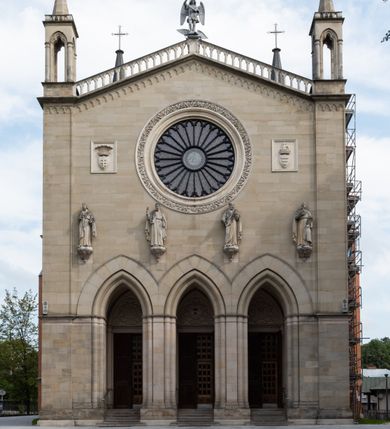 Zdjęcie nr 24: Kościół z cegły i kamienia. Na rzucie krzyża łacińskiego, jednonawowy z wciągniętymi do wnętrza przyporami. Prezbiterium krótkie, zamknięte pięcioma bokami ośmioboku. Korpus jednonawowy, czteroprzęsłowy, po bokach z płytkimi wnękami-kaplicami pomiędzy przyporami, poprzedzony od zach. przedsionkiem. Do pierwszego przęsła dostawione dwie symetryczne, trójboczne kaplice, nad nimi dwie czworoboczne wieże. Zakrystia przy prezbiterium na osi kościoła. Artykulacja ścian wnętrza za pomocą filarów opiętych półkolumnami z kapitelami z motywów liści. Między filarami rozpięte ostrołukowe arkady tworzące płytkie wnęki. Pierwsze przęsło wyróżnione przy pomocy masywnych filarów, ujętych niemal pełnoplastycznymi kolumnami. Okna ostrołukowe, dwudzielne z maswerkami, wsparte na gzymsach. Sklepienia krzyżowo-żebrowe na zaostrzonych gurtach. Kaplice artykułowane analogicznie do nawy kościoła, ze sklepieniami gwiaździstymi. Przedsionek otwiera się do kościoła trzema portalami ostrołukowymi opiętymi kolumnami. W polach archiwolt płaskorzeźby: Boże Narodzenie, Ukrzyżowanie, Wniebowstąpienie (K. Ceptowski).  W prezbiterium, na osi kościoła prostokątny otwór drzwiowy prowadzący do zakrystii. Chór muzyczny umieszczony nad kruchtą kościoła, na rzucie prostokąta, z kamienną balustradą maswerkową. Fasada kamienna, trójosiowa, zamknięta trójkątnie, flankowana lizenami przechodzącymi w ażurowe wieżyczki-latarnie, na rzucie kwadratu. Wieżyczki zwieńczone gzymsem i balustradą arkadową, hełmy ostrosłupowy zakończony iglicą. W dolnej części trzy filarowe arkady ostrołukowe, otwierające się do kruchty, sklepienie kruchty krzyżowo-żebrowe. Nad arkadami wejściowymi trzy tonda: litery IHS, Oko Opatrzności i splecione litery imienia Maria. Pośrodku na osi kościoła duża rozeta z maswerkiem, profilowana, otoczona pierścieniem wypełnionym stylizowanym ornamentem roślinnym. Ponad arkadami pełnoplastyczne figury czterech ewangelistów ustawionych na konsolach z rzeźbionymi atrybutami (F. Kuhn). Po bokach rozety prostokątne płyciny z traczami herbowymi Potockich i Branickich. U góry, na osi fasady figura Archanioła Michała. Elewacje na kamiennym cokole, z gzymsem kapnikowym, opięte prostokątnymi przyporami zwieńczonymi kamiennymi nakrywami. W górnej części kamienny fryz arkadkowy. Nad nim gzyms koronujący podtrzymujący ażurową, arkadową balustradę. Przy prezbiterium kaplice zamknięte trójbocznie, prezbiterium zamknięte pięciobocznie. Zakrystia na osi prezbiterium, na rzucie prostokąta, zwieńczona sygnaturką i ceglanym kominem. Po bokach prostokątne aneksy, południowy aneks - trzy okna ostrołukowe w kamiennej opasce, w środkowym przedstawienie Ukrzyżowanego Chrystusa. W północnym aneksie pojedyncze analogiczne okno. Okna ostrołukowe w profilowanych kamiennych opaskach, pomiędzy nimi a gzymsem koronującym mniejsze ostrołukowe w uskokowych arkadach. Nad kaplicami bocznymi dwie symetryczne wieże na rzucie kwadratu, w połowie wysokości kamienny gzyms z fryzem arkadkowym. Okna ostrołukowe w kamiennej opasce. Całość zwieńczona ślepym fryzem arkadkowym, wyżej gzyms dźwigający ażurową arkadkową balustradę. Hełmy ostrosłupowe, miedziane. Zakrystia na rzucie prostokąta, nakryta sklepieniem kolebkowym zaostrzonym i krzyżowym z lunetami , oddzielone gurtem. Portale od wschodu i zachodu prostokątne zamknięte łukiem ostrym. Okna ostrołukowe.