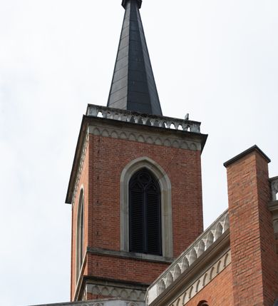 Zdjęcie nr 21: Kościół z cegły i kamienia. Na rzucie krzyża łacińskiego, jednonawowy z wciągniętymi do wnętrza przyporami. Prezbiterium krótkie, zamknięte pięcioma bokami ośmioboku. Korpus jednonawowy, czteroprzęsłowy, po bokach z płytkimi wnękami-kaplicami pomiędzy przyporami, poprzedzony od zach. przedsionkiem. Do pierwszego przęsła dostawione dwie symetryczne, trójboczne kaplice, nad nimi dwie czworoboczne wieże. Zakrystia przy prezbiterium na osi kościoła. Artykulacja ścian wnętrza za pomocą filarów opiętych półkolumnami z kapitelami z motywów liści. Między filarami rozpięte ostrołukowe arkady tworzące płytkie wnęki. Pierwsze przęsło wyróżnione przy pomocy masywnych filarów, ujętych niemal pełnoplastycznymi kolumnami. Okna ostrołukowe, dwudzielne z maswerkami, wsparte na gzymsach. Sklepienia krzyżowo-żebrowe na zaostrzonych gurtach. Kaplice artykułowane analogicznie do nawy kościoła, ze sklepieniami gwiaździstymi. Przedsionek otwiera się do kościoła trzema portalami ostrołukowymi opiętymi kolumnami. W polach archiwolt płaskorzeźby: Boże Narodzenie, Ukrzyżowanie, Wniebowstąpienie (K. Ceptowski).  W prezbiterium, na osi kościoła prostokątny otwór drzwiowy prowadzący do zakrystii. Chór muzyczny umieszczony nad kruchtą kościoła, na rzucie prostokąta, z kamienną balustradą maswerkową. Fasada kamienna, trójosiowa, zamknięta trójkątnie, flankowana lizenami przechodzącymi w ażurowe wieżyczki-latarnie, na rzucie kwadratu. Wieżyczki zwieńczone gzymsem i balustradą arkadową, hełmy ostrosłupowy zakończony iglicą. W dolnej części trzy filarowe arkady ostrołukowe, otwierające się do kruchty, sklepienie kruchty krzyżowo-żebrowe. Nad arkadami wejściowymi trzy tonda: litery IHS, Oko Opatrzności i splecione litery imienia Maria. Pośrodku na osi kościoła duża rozeta z maswerkiem, profilowana, otoczona pierścieniem wypełnionym stylizowanym ornamentem roślinnym. Ponad arkadami pełnoplastyczne figury czterech ewangelistów ustawionych na konsolach z rzeźbionymi atrybutami (F. Kuhn). Po bokach rozety prostokątne płyciny z traczami herbowymi Potockich i Branickich. U góry, na osi fasady figura Archanioła Michała. Elewacje na kamiennym cokole, z gzymsem kapnikowym, opięte prostokątnymi przyporami zwieńczonymi kamiennymi nakrywami. W górnej części kamienny fryz arkadkowy. Nad nim gzyms koronujący podtrzymujący ażurową, arkadową balustradę. Przy prezbiterium kaplice zamknięte trójbocznie, prezbiterium zamknięte pięciobocznie. Zakrystia na osi prezbiterium, na rzucie prostokąta, zwieńczona sygnaturką i ceglanym kominem. Po bokach prostokątne aneksy, południowy aneks - trzy okna ostrołukowe w kamiennej opasce, w środkowym przedstawienie Ukrzyżowanego Chrystusa. W północnym aneksie pojedyncze analogiczne okno. Okna ostrołukowe w profilowanych kamiennych opaskach, pomiędzy nimi a gzymsem koronującym mniejsze ostrołukowe w uskokowych arkadach. Nad kaplicami bocznymi dwie symetryczne wieże na rzucie kwadratu, w połowie wysokości kamienny gzyms z fryzem arkadkowym. Okna ostrołukowe w kamiennej opasce. Całość zwieńczona ślepym fryzem arkadkowym, wyżej gzyms dźwigający ażurową arkadkową balustradę. Hełmy ostrosłupowe, miedziane. Zakrystia na rzucie prostokąta, nakryta sklepieniem kolebkowym zaostrzonym i krzyżowym z lunetami , oddzielone gurtem. Portale od wschodu i zachodu prostokątne zamknięte łukiem ostrym. Okna ostrołukowe.