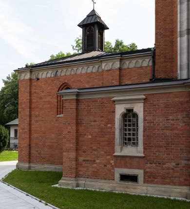Zdjęcie nr 3: Kościół z cegły i kamienia. Na rzucie krzyża łacińskiego, jednonawowy z wciągniętymi do wnętrza przyporami. Prezbiterium krótkie, zamknięte pięcioma bokami ośmioboku. Korpus jednonawowy, czteroprzęsłowy, po bokach z płytkimi wnękami-kaplicami pomiędzy przyporami, poprzedzony od zach. przedsionkiem. Do pierwszego przęsła dostawione dwie symetryczne, trójboczne kaplice, nad nimi dwie czworoboczne wieże. Zakrystia przy prezbiterium na osi kościoła. Artykulacja ścian wnętrza za pomocą filarów opiętych półkolumnami z kapitelami z motywów liści. Między filarami rozpięte ostrołukowe arkady tworzące płytkie wnęki. Pierwsze przęsło wyróżnione przy pomocy masywnych filarów, ujętych niemal pełnoplastycznymi kolumnami. Okna ostrołukowe, dwudzielne z maswerkami, wsparte na gzymsach. Sklepienia krzyżowo-żebrowe na zaostrzonych gurtach. Kaplice artykułowane analogicznie do nawy kościoła, ze sklepieniami gwiaździstymi. Przedsionek otwiera się do kościoła trzema portalami ostrołukowymi opiętymi kolumnami. W polach archiwolt płaskorzeźby: Boże Narodzenie, Ukrzyżowanie, Wniebowstąpienie (K. Ceptowski).  W prezbiterium, na osi kościoła prostokątny otwór drzwiowy prowadzący do zakrystii. Chór muzyczny umieszczony nad kruchtą kościoła, na rzucie prostokąta, z kamienną balustradą maswerkową. Fasada kamienna, trójosiowa, zamknięta trójkątnie, flankowana lizenami przechodzącymi w ażurowe wieżyczki-latarnie, na rzucie kwadratu. Wieżyczki zwieńczone gzymsem i balustradą arkadową, hełmy ostrosłupowy zakończony iglicą. W dolnej części trzy filarowe arkady ostrołukowe, otwierające się do kruchty, sklepienie kruchty krzyżowo-żebrowe. Nad arkadami wejściowymi trzy tonda: litery IHS, Oko Opatrzności i splecione litery imienia Maria. Pośrodku na osi kościoła duża rozeta z maswerkiem, profilowana, otoczona pierścieniem wypełnionym stylizowanym ornamentem roślinnym. Ponad arkadami pełnoplastyczne figury czterech ewangelistów ustawionych na konsolach z rzeźbionymi atrybutami (F. Kuhn). Po bokach rozety prostokątne płyciny z traczami herbowymi Potockich i Branickich. U góry, na osi fasady figura Archanioła Michała. Elewacje na kamiennym cokole, z gzymsem kapnikowym, opięte prostokątnymi przyporami zwieńczonymi kamiennymi nakrywami. W górnej części kamienny fryz arkadkowy. Nad nim gzyms koronujący podtrzymujący ażurową, arkadową balustradę. Przy prezbiterium kaplice zamknięte trójbocznie, prezbiterium zamknięte pięciobocznie. Zakrystia na osi prezbiterium, na rzucie prostokąta, zwieńczona sygnaturką i ceglanym kominem. Po bokach prostokątne aneksy, południowy aneks - trzy okna ostrołukowe w kamiennej opasce, w środkowym przedstawienie Ukrzyżowanego Chrystusa. W północnym aneksie pojedyncze analogiczne okno. Okna ostrołukowe w profilowanych kamiennych opaskach, pomiędzy nimi a gzymsem koronującym mniejsze ostrołukowe w uskokowych arkadach. Nad kaplicami bocznymi dwie symetryczne wieże na rzucie kwadratu, w połowie wysokości kamienny gzyms z fryzem arkadkowym. Okna ostrołukowe w kamiennej opasce. Całość zwieńczona ślepym fryzem arkadkowym, wyżej gzyms dźwigający ażurową arkadkową balustradę. Hełmy ostrosłupowe, miedziane. Zakrystia na rzucie prostokąta, nakryta sklepieniem kolebkowym zaostrzonym i krzyżowym z lunetami , oddzielone gurtem. Portale od wschodu i zachodu prostokątne zamknięte łukiem ostrym. Okna ostrołukowe.
