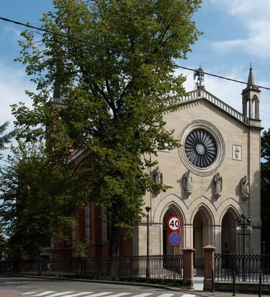 Zdjęcie nr 35: Kościół z cegły i kamienia. Na rzucie krzyża łacińskiego, jednonawowy z wciągniętymi do wnętrza przyporami. Prezbiterium krótkie, zamknięte pięcioma bokami ośmioboku. Korpus jednonawowy, czteroprzęsłowy, po bokach z płytkimi wnękami-kaplicami pomiędzy przyporami, poprzedzony od zach. przedsionkiem. Do pierwszego przęsła dostawione dwie symetryczne, trójboczne kaplice, nad nimi dwie czworoboczne wieże. Zakrystia przy prezbiterium na osi kościoła. Artykulacja ścian wnętrza za pomocą filarów opiętych półkolumnami z kapitelami z motywów liści. Między filarami rozpięte ostrołukowe arkady tworzące płytkie wnęki. Pierwsze przęsło wyróżnione przy pomocy masywnych filarów, ujętych niemal pełnoplastycznymi kolumnami. Okna ostrołukowe, dwudzielne z maswerkami, wsparte na gzymsach. Sklepienia krzyżowo-żebrowe na zaostrzonych gurtach. Kaplice artykułowane analogicznie do nawy kościoła, ze sklepieniami gwiaździstymi. Przedsionek otwiera się do kościoła trzema portalami ostrołukowymi opiętymi kolumnami. W polach archiwolt płaskorzeźby: Boże Narodzenie, Ukrzyżowanie, Wniebowstąpienie (K. Ceptowski).  W prezbiterium, na osi kościoła prostokątny otwór drzwiowy prowadzący do zakrystii. Chór muzyczny umieszczony nad kruchtą kościoła, na rzucie prostokąta, z kamienną balustradą maswerkową. Fasada kamienna, trójosiowa, zamknięta trójkątnie, flankowana lizenami przechodzącymi w ażurowe wieżyczki-latarnie, na rzucie kwadratu. Wieżyczki zwieńczone gzymsem i balustradą arkadową, hełmy ostrosłupowy zakończony iglicą. W dolnej części trzy filarowe arkady ostrołukowe, otwierające się do kruchty, sklepienie kruchty krzyżowo-żebrowe. Nad arkadami wejściowymi trzy tonda: litery IHS, Oko Opatrzności i splecione litery imienia Maria. Pośrodku na osi kościoła duża rozeta z maswerkiem, profilowana, otoczona pierścieniem wypełnionym stylizowanym ornamentem roślinnym. Ponad arkadami pełnoplastyczne figury czterech ewangelistów ustawionych na konsolach z rzeźbionymi atrybutami (F. Kuhn). Po bokach rozety prostokątne płyciny z traczami herbowymi Potockich i Branickich. U góry, na osi fasady figura Archanioła Michała. Elewacje na kamiennym cokole, z gzymsem kapnikowym, opięte prostokątnymi przyporami zwieńczonymi kamiennymi nakrywami. W górnej części kamienny fryz arkadkowy. Nad nim gzyms koronujący podtrzymujący ażurową, arkadową balustradę. Przy prezbiterium kaplice zamknięte trójbocznie, prezbiterium zamknięte pięciobocznie. Zakrystia na osi prezbiterium, na rzucie prostokąta, zwieńczona sygnaturką i ceglanym kominem. Po bokach prostokątne aneksy, południowy aneks - trzy okna ostrołukowe w kamiennej opasce, w środkowym przedstawienie Ukrzyżowanego Chrystusa. W północnym aneksie pojedyncze analogiczne okno. Okna ostrołukowe w profilowanych kamiennych opaskach, pomiędzy nimi a gzymsem koronującym mniejsze ostrołukowe w uskokowych arkadach. Nad kaplicami bocznymi dwie symetryczne wieże na rzucie kwadratu, w połowie wysokości kamienny gzyms z fryzem arkadkowym. Okna ostrołukowe w kamiennej opasce. Całość zwieńczona ślepym fryzem arkadkowym, wyżej gzyms dźwigający ażurową arkadkową balustradę. Hełmy ostrosłupowe, miedziane. Zakrystia na rzucie prostokąta, nakryta sklepieniem kolebkowym zaostrzonym i krzyżowym z lunetami , oddzielone gurtem. Portale od wschodu i zachodu prostokątne zamknięte łukiem ostrym. Okna ostrołukowe.