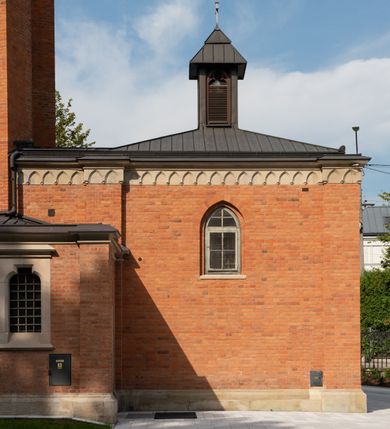 Zdjęcie nr 15: Kościół z cegły i kamienia. Na rzucie krzyża łacińskiego, jednonawowy z wciągniętymi do wnętrza przyporami. Prezbiterium krótkie, zamknięte pięcioma bokami ośmioboku. Korpus jednonawowy, czteroprzęsłowy, po bokach z płytkimi wnękami-kaplicami pomiędzy przyporami, poprzedzony od zach. przedsionkiem. Do pierwszego przęsła dostawione dwie symetryczne, trójboczne kaplice, nad nimi dwie czworoboczne wieże. Zakrystia przy prezbiterium na osi kościoła. Artykulacja ścian wnętrza za pomocą filarów opiętych półkolumnami z kapitelami z motywów liści. Między filarami rozpięte ostrołukowe arkady tworzące płytkie wnęki. Pierwsze przęsło wyróżnione przy pomocy masywnych filarów, ujętych niemal pełnoplastycznymi kolumnami. Okna ostrołukowe, dwudzielne z maswerkami, wsparte na gzymsach. Sklepienia krzyżowo-żebrowe na zaostrzonych gurtach. Kaplice artykułowane analogicznie do nawy kościoła, ze sklepieniami gwiaździstymi. Przedsionek otwiera się do kościoła trzema portalami ostrołukowymi opiętymi kolumnami. W polach archiwolt płaskorzeźby: Boże Narodzenie, Ukrzyżowanie, Wniebowstąpienie (K. Ceptowski).  W prezbiterium, na osi kościoła prostokątny otwór drzwiowy prowadzący do zakrystii. Chór muzyczny umieszczony nad kruchtą kościoła, na rzucie prostokąta, z kamienną balustradą maswerkową. Fasada kamienna, trójosiowa, zamknięta trójkątnie, flankowana lizenami przechodzącymi w ażurowe wieżyczki-latarnie, na rzucie kwadratu. Wieżyczki zwieńczone gzymsem i balustradą arkadową, hełmy ostrosłupowy zakończony iglicą. W dolnej części trzy filarowe arkady ostrołukowe, otwierające się do kruchty, sklepienie kruchty krzyżowo-żebrowe. Nad arkadami wejściowymi trzy tonda: litery IHS, Oko Opatrzności i splecione litery imienia Maria. Pośrodku na osi kościoła duża rozeta z maswerkiem, profilowana, otoczona pierścieniem wypełnionym stylizowanym ornamentem roślinnym. Ponad arkadami pełnoplastyczne figury czterech ewangelistów ustawionych na konsolach z rzeźbionymi atrybutami (F. Kuhn). Po bokach rozety prostokątne płyciny z traczami herbowymi Potockich i Branickich. U góry, na osi fasady figura Archanioła Michała. Elewacje na kamiennym cokole, z gzymsem kapnikowym, opięte prostokątnymi przyporami zwieńczonymi kamiennymi nakrywami. W górnej części kamienny fryz arkadkowy. Nad nim gzyms koronujący podtrzymujący ażurową, arkadową balustradę. Przy prezbiterium kaplice zamknięte trójbocznie, prezbiterium zamknięte pięciobocznie. Zakrystia na osi prezbiterium, na rzucie prostokąta, zwieńczona sygnaturką i ceglanym kominem. Po bokach prostokątne aneksy, południowy aneks - trzy okna ostrołukowe w kamiennej opasce, w środkowym przedstawienie Ukrzyżowanego Chrystusa. W północnym aneksie pojedyncze analogiczne okno. Okna ostrołukowe w profilowanych kamiennych opaskach, pomiędzy nimi a gzymsem koronującym mniejsze ostrołukowe w uskokowych arkadach. Nad kaplicami bocznymi dwie symetryczne wieże na rzucie kwadratu, w połowie wysokości kamienny gzyms z fryzem arkadkowym. Okna ostrołukowe w kamiennej opasce. Całość zwieńczona ślepym fryzem arkadkowym, wyżej gzyms dźwigający ażurową arkadkową balustradę. Hełmy ostrosłupowe, miedziane. Zakrystia na rzucie prostokąta, nakryta sklepieniem kolebkowym zaostrzonym i krzyżowym z lunetami , oddzielone gurtem. Portale od wschodu i zachodu prostokątne zamknięte łukiem ostrym. Okna ostrołukowe.