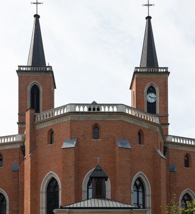 Zdjęcie nr 6: Kościół z cegły i kamienia. Na rzucie krzyża łacińskiego, jednonawowy z wciągniętymi do wnętrza przyporami. Prezbiterium krótkie, zamknięte pięcioma bokami ośmioboku. Korpus jednonawowy, czteroprzęsłowy, po bokach z płytkimi wnękami-kaplicami pomiędzy przyporami, poprzedzony od zach. przedsionkiem. Do pierwszego przęsła dostawione dwie symetryczne, trójboczne kaplice, nad nimi dwie czworoboczne wieże. Zakrystia przy prezbiterium na osi kościoła. Artykulacja ścian wnętrza za pomocą filarów opiętych półkolumnami z kapitelami z motywów liści. Między filarami rozpięte ostrołukowe arkady tworzące płytkie wnęki. Pierwsze przęsło wyróżnione przy pomocy masywnych filarów, ujętych niemal pełnoplastycznymi kolumnami. Okna ostrołukowe, dwudzielne z maswerkami, wsparte na gzymsach. Sklepienia krzyżowo-żebrowe na zaostrzonych gurtach. Kaplice artykułowane analogicznie do nawy kościoła, ze sklepieniami gwiaździstymi. Przedsionek otwiera się do kościoła trzema portalami ostrołukowymi opiętymi kolumnami. W polach archiwolt płaskorzeźby: Boże Narodzenie, Ukrzyżowanie, Wniebowstąpienie (K. Ceptowski).  W prezbiterium, na osi kościoła prostokątny otwór drzwiowy prowadzący do zakrystii. Chór muzyczny umieszczony nad kruchtą kościoła, na rzucie prostokąta, z kamienną balustradą maswerkową. Fasada kamienna, trójosiowa, zamknięta trójkątnie, flankowana lizenami przechodzącymi w ażurowe wieżyczki-latarnie, na rzucie kwadratu. Wieżyczki zwieńczone gzymsem i balustradą arkadową, hełmy ostrosłupowy zakończony iglicą. W dolnej części trzy filarowe arkady ostrołukowe, otwierające się do kruchty, sklepienie kruchty krzyżowo-żebrowe. Nad arkadami wejściowymi trzy tonda: litery IHS, Oko Opatrzności i splecione litery imienia Maria. Pośrodku na osi kościoła duża rozeta z maswerkiem, profilowana, otoczona pierścieniem wypełnionym stylizowanym ornamentem roślinnym. Ponad arkadami pełnoplastyczne figury czterech ewangelistów ustawionych na konsolach z rzeźbionymi atrybutami (F. Kuhn). Po bokach rozety prostokątne płyciny z traczami herbowymi Potockich i Branickich. U góry, na osi fasady figura Archanioła Michała. Elewacje na kamiennym cokole, z gzymsem kapnikowym, opięte prostokątnymi przyporami zwieńczonymi kamiennymi nakrywami. W górnej części kamienny fryz arkadkowy. Nad nim gzyms koronujący podtrzymujący ażurową, arkadową balustradę. Przy prezbiterium kaplice zamknięte trójbocznie, prezbiterium zamknięte pięciobocznie. Zakrystia na osi prezbiterium, na rzucie prostokąta, zwieńczona sygnaturką i ceglanym kominem. Po bokach prostokątne aneksy, południowy aneks - trzy okna ostrołukowe w kamiennej opasce, w środkowym przedstawienie Ukrzyżowanego Chrystusa. W północnym aneksie pojedyncze analogiczne okno. Okna ostrołukowe w profilowanych kamiennych opaskach, pomiędzy nimi a gzymsem koronującym mniejsze ostrołukowe w uskokowych arkadach. Nad kaplicami bocznymi dwie symetryczne wieże na rzucie kwadratu, w połowie wysokości kamienny gzyms z fryzem arkadkowym. Okna ostrołukowe w kamiennej opasce. Całość zwieńczona ślepym fryzem arkadkowym, wyżej gzyms dźwigający ażurową arkadkową balustradę. Hełmy ostrosłupowe, miedziane. Zakrystia na rzucie prostokąta, nakryta sklepieniem kolebkowym zaostrzonym i krzyżowym z lunetami , oddzielone gurtem. Portale od wschodu i zachodu prostokątne zamknięte łukiem ostrym. Okna ostrołukowe.