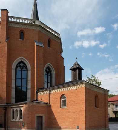 Zdjęcie nr 9: Kościół z cegły i kamienia. Na rzucie krzyża łacińskiego, jednonawowy z wciągniętymi do wnętrza przyporami. Prezbiterium krótkie, zamknięte pięcioma bokami ośmioboku. Korpus jednonawowy, czteroprzęsłowy, po bokach z płytkimi wnękami-kaplicami pomiędzy przyporami, poprzedzony od zach. przedsionkiem. Do pierwszego przęsła dostawione dwie symetryczne, trójboczne kaplice, nad nimi dwie czworoboczne wieże. Zakrystia przy prezbiterium na osi kościoła. Artykulacja ścian wnętrza za pomocą filarów opiętych półkolumnami z kapitelami z motywów liści. Między filarami rozpięte ostrołukowe arkady tworzące płytkie wnęki. Pierwsze przęsło wyróżnione przy pomocy masywnych filarów, ujętych niemal pełnoplastycznymi kolumnami. Okna ostrołukowe, dwudzielne z maswerkami, wsparte na gzymsach. Sklepienia krzyżowo-żebrowe na zaostrzonych gurtach. Kaplice artykułowane analogicznie do nawy kościoła, ze sklepieniami gwiaździstymi. Przedsionek otwiera się do kościoła trzema portalami ostrołukowymi opiętymi kolumnami. W polach archiwolt płaskorzeźby: Boże Narodzenie, Ukrzyżowanie, Wniebowstąpienie (K. Ceptowski).  W prezbiterium, na osi kościoła prostokątny otwór drzwiowy prowadzący do zakrystii. Chór muzyczny umieszczony nad kruchtą kościoła, na rzucie prostokąta, z kamienną balustradą maswerkową. Fasada kamienna, trójosiowa, zamknięta trójkątnie, flankowana lizenami przechodzącymi w ażurowe wieżyczki-latarnie, na rzucie kwadratu. Wieżyczki zwieńczone gzymsem i balustradą arkadową, hełmy ostrosłupowy zakończony iglicą. W dolnej części trzy filarowe arkady ostrołukowe, otwierające się do kruchty, sklepienie kruchty krzyżowo-żebrowe. Nad arkadami wejściowymi trzy tonda: litery IHS, Oko Opatrzności i splecione litery imienia Maria. Pośrodku na osi kościoła duża rozeta z maswerkiem, profilowana, otoczona pierścieniem wypełnionym stylizowanym ornamentem roślinnym. Ponad arkadami pełnoplastyczne figury czterech ewangelistów ustawionych na konsolach z rzeźbionymi atrybutami (F. Kuhn). Po bokach rozety prostokątne płyciny z traczami herbowymi Potockich i Branickich. U góry, na osi fasady figura Archanioła Michała. Elewacje na kamiennym cokole, z gzymsem kapnikowym, opięte prostokątnymi przyporami zwieńczonymi kamiennymi nakrywami. W górnej części kamienny fryz arkadkowy. Nad nim gzyms koronujący podtrzymujący ażurową, arkadową balustradę. Przy prezbiterium kaplice zamknięte trójbocznie, prezbiterium zamknięte pięciobocznie. Zakrystia na osi prezbiterium, na rzucie prostokąta, zwieńczona sygnaturką i ceglanym kominem. Po bokach prostokątne aneksy, południowy aneks - trzy okna ostrołukowe w kamiennej opasce, w środkowym przedstawienie Ukrzyżowanego Chrystusa. W północnym aneksie pojedyncze analogiczne okno. Okna ostrołukowe w profilowanych kamiennych opaskach, pomiędzy nimi a gzymsem koronującym mniejsze ostrołukowe w uskokowych arkadach. Nad kaplicami bocznymi dwie symetryczne wieże na rzucie kwadratu, w połowie wysokości kamienny gzyms z fryzem arkadkowym. Okna ostrołukowe w kamiennej opasce. Całość zwieńczona ślepym fryzem arkadkowym, wyżej gzyms dźwigający ażurową arkadkową balustradę. Hełmy ostrosłupowe, miedziane. Zakrystia na rzucie prostokąta, nakryta sklepieniem kolebkowym zaostrzonym i krzyżowym z lunetami , oddzielone gurtem. Portale od wschodu i zachodu prostokątne zamknięte łukiem ostrym. Okna ostrołukowe.