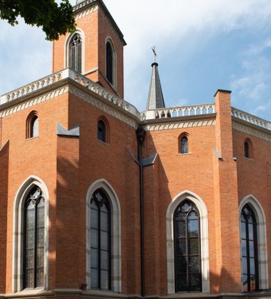 Zdjęcie nr 17: Kościół z cegły i kamienia. Na rzucie krzyża łacińskiego, jednonawowy z wciągniętymi do wnętrza przyporami. Prezbiterium krótkie, zamknięte pięcioma bokami ośmioboku. Korpus jednonawowy, czteroprzęsłowy, po bokach z płytkimi wnękami-kaplicami pomiędzy przyporami, poprzedzony od zach. przedsionkiem. Do pierwszego przęsła dostawione dwie symetryczne, trójboczne kaplice, nad nimi dwie czworoboczne wieże. Zakrystia przy prezbiterium na osi kościoła. Artykulacja ścian wnętrza za pomocą filarów opiętych półkolumnami z kapitelami z motywów liści. Między filarami rozpięte ostrołukowe arkady tworzące płytkie wnęki. Pierwsze przęsło wyróżnione przy pomocy masywnych filarów, ujętych niemal pełnoplastycznymi kolumnami. Okna ostrołukowe, dwudzielne z maswerkami, wsparte na gzymsach. Sklepienia krzyżowo-żebrowe na zaostrzonych gurtach. Kaplice artykułowane analogicznie do nawy kościoła, ze sklepieniami gwiaździstymi. Przedsionek otwiera się do kościoła trzema portalami ostrołukowymi opiętymi kolumnami. W polach archiwolt płaskorzeźby: Boże Narodzenie, Ukrzyżowanie, Wniebowstąpienie (K. Ceptowski).  W prezbiterium, na osi kościoła prostokątny otwór drzwiowy prowadzący do zakrystii. Chór muzyczny umieszczony nad kruchtą kościoła, na rzucie prostokąta, z kamienną balustradą maswerkową. Fasada kamienna, trójosiowa, zamknięta trójkątnie, flankowana lizenami przechodzącymi w ażurowe wieżyczki-latarnie, na rzucie kwadratu. Wieżyczki zwieńczone gzymsem i balustradą arkadową, hełmy ostrosłupowy zakończony iglicą. W dolnej części trzy filarowe arkady ostrołukowe, otwierające się do kruchty, sklepienie kruchty krzyżowo-żebrowe. Nad arkadami wejściowymi trzy tonda: litery IHS, Oko Opatrzności i splecione litery imienia Maria. Pośrodku na osi kościoła duża rozeta z maswerkiem, profilowana, otoczona pierścieniem wypełnionym stylizowanym ornamentem roślinnym. Ponad arkadami pełnoplastyczne figury czterech ewangelistów ustawionych na konsolach z rzeźbionymi atrybutami (F. Kuhn). Po bokach rozety prostokątne płyciny z traczami herbowymi Potockich i Branickich. U góry, na osi fasady figura Archanioła Michała. Elewacje na kamiennym cokole, z gzymsem kapnikowym, opięte prostokątnymi przyporami zwieńczonymi kamiennymi nakrywami. W górnej części kamienny fryz arkadkowy. Nad nim gzyms koronujący podtrzymujący ażurową, arkadową balustradę. Przy prezbiterium kaplice zamknięte trójbocznie, prezbiterium zamknięte pięciobocznie. Zakrystia na osi prezbiterium, na rzucie prostokąta, zwieńczona sygnaturką i ceglanym kominem. Po bokach prostokątne aneksy, południowy aneks - trzy okna ostrołukowe w kamiennej opasce, w środkowym przedstawienie Ukrzyżowanego Chrystusa. W północnym aneksie pojedyncze analogiczne okno. Okna ostrołukowe w profilowanych kamiennych opaskach, pomiędzy nimi a gzymsem koronującym mniejsze ostrołukowe w uskokowych arkadach. Nad kaplicami bocznymi dwie symetryczne wieże na rzucie kwadratu, w połowie wysokości kamienny gzyms z fryzem arkadkowym. Okna ostrołukowe w kamiennej opasce. Całość zwieńczona ślepym fryzem arkadkowym, wyżej gzyms dźwigający ażurową arkadkową balustradę. Hełmy ostrosłupowe, miedziane. Zakrystia na rzucie prostokąta, nakryta sklepieniem kolebkowym zaostrzonym i krzyżowym z lunetami , oddzielone gurtem. Portale od wschodu i zachodu prostokątne zamknięte łukiem ostrym. Okna ostrołukowe.