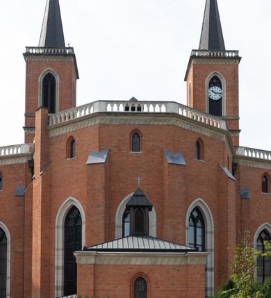 Zdjęcie nr 5: Kościół z cegły i kamienia. Na rzucie krzyża łacińskiego, jednonawowy z wciągniętymi do wnętrza przyporami. Prezbiterium krótkie, zamknięte pięcioma bokami ośmioboku. Korpus jednonawowy, czteroprzęsłowy, po bokach z płytkimi wnękami-kaplicami pomiędzy przyporami, poprzedzony od zach. przedsionkiem. Do pierwszego przęsła dostawione dwie symetryczne, trójboczne kaplice, nad nimi dwie czworoboczne wieże. Zakrystia przy prezbiterium na osi kościoła. Artykulacja ścian wnętrza za pomocą filarów opiętych półkolumnami z kapitelami z motywów liści. Między filarami rozpięte ostrołukowe arkady tworzące płytkie wnęki. Pierwsze przęsło wyróżnione przy pomocy masywnych filarów, ujętych niemal pełnoplastycznymi kolumnami. Okna ostrołukowe, dwudzielne z maswerkami, wsparte na gzymsach. Sklepienia krzyżowo-żebrowe na zaostrzonych gurtach. Kaplice artykułowane analogicznie do nawy kościoła, ze sklepieniami gwiaździstymi. Przedsionek otwiera się do kościoła trzema portalami ostrołukowymi opiętymi kolumnami. W polach archiwolt płaskorzeźby: Boże Narodzenie, Ukrzyżowanie, Wniebowstąpienie (K. Ceptowski).  W prezbiterium, na osi kościoła prostokątny otwór drzwiowy prowadzący do zakrystii. Chór muzyczny umieszczony nad kruchtą kościoła, na rzucie prostokąta, z kamienną balustradą maswerkową. Fasada kamienna, trójosiowa, zamknięta trójkątnie, flankowana lizenami przechodzącymi w ażurowe wieżyczki-latarnie, na rzucie kwadratu. Wieżyczki zwieńczone gzymsem i balustradą arkadową, hełmy ostrosłupowy zakończony iglicą. W dolnej części trzy filarowe arkady ostrołukowe, otwierające się do kruchty, sklepienie kruchty krzyżowo-żebrowe. Nad arkadami wejściowymi trzy tonda: litery IHS, Oko Opatrzności i splecione litery imienia Maria. Pośrodku na osi kościoła duża rozeta z maswerkiem, profilowana, otoczona pierścieniem wypełnionym stylizowanym ornamentem roślinnym. Ponad arkadami pełnoplastyczne figury czterech ewangelistów ustawionych na konsolach z rzeźbionymi atrybutami (F. Kuhn). Po bokach rozety prostokątne płyciny z traczami herbowymi Potockich i Branickich. U góry, na osi fasady figura Archanioła Michała. Elewacje na kamiennym cokole, z gzymsem kapnikowym, opięte prostokątnymi przyporami zwieńczonymi kamiennymi nakrywami. W górnej części kamienny fryz arkadkowy. Nad nim gzyms koronujący podtrzymujący ażurową, arkadową balustradę. Przy prezbiterium kaplice zamknięte trójbocznie, prezbiterium zamknięte pięciobocznie. Zakrystia na osi prezbiterium, na rzucie prostokąta, zwieńczona sygnaturką i ceglanym kominem. Po bokach prostokątne aneksy, południowy aneks - trzy okna ostrołukowe w kamiennej opasce, w środkowym przedstawienie Ukrzyżowanego Chrystusa. W północnym aneksie pojedyncze analogiczne okno. Okna ostrołukowe w profilowanych kamiennych opaskach, pomiędzy nimi a gzymsem koronującym mniejsze ostrołukowe w uskokowych arkadach. Nad kaplicami bocznymi dwie symetryczne wieże na rzucie kwadratu, w połowie wysokości kamienny gzyms z fryzem arkadkowym. Okna ostrołukowe w kamiennej opasce. Całość zwieńczona ślepym fryzem arkadkowym, wyżej gzyms dźwigający ażurową arkadkową balustradę. Hełmy ostrosłupowe, miedziane. Zakrystia na rzucie prostokąta, nakryta sklepieniem kolebkowym zaostrzonym i krzyżowym z lunetami , oddzielone gurtem. Portale od wschodu i zachodu prostokątne zamknięte łukiem ostrym. Okna ostrołukowe.