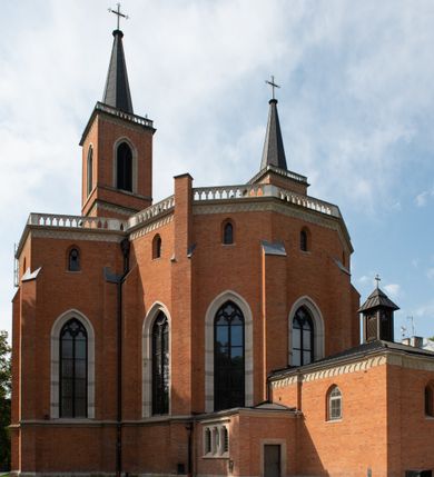 Zdjęcie nr 7: Kościół z cegły i kamienia. Na rzucie krzyża łacińskiego, jednonawowy z wciągniętymi do wnętrza przyporami. Prezbiterium krótkie, zamknięte pięcioma bokami ośmioboku. Korpus jednonawowy, czteroprzęsłowy, po bokach z płytkimi wnękami-kaplicami pomiędzy przyporami, poprzedzony od zach. przedsionkiem. Do pierwszego przęsła dostawione dwie symetryczne, trójboczne kaplice, nad nimi dwie czworoboczne wieże. Zakrystia przy prezbiterium na osi kościoła. Artykulacja ścian wnętrza za pomocą filarów opiętych półkolumnami z kapitelami z motywów liści. Między filarami rozpięte ostrołukowe arkady tworzące płytkie wnęki. Pierwsze przęsło wyróżnione przy pomocy masywnych filarów, ujętych niemal pełnoplastycznymi kolumnami. Okna ostrołukowe, dwudzielne z maswerkami, wsparte na gzymsach. Sklepienia krzyżowo-żebrowe na zaostrzonych gurtach. Kaplice artykułowane analogicznie do nawy kościoła, ze sklepieniami gwiaździstymi. Przedsionek otwiera się do kościoła trzema portalami ostrołukowymi opiętymi kolumnami. W polach archiwolt płaskorzeźby: Boże Narodzenie, Ukrzyżowanie, Wniebowstąpienie (K. Ceptowski).  W prezbiterium, na osi kościoła prostokątny otwór drzwiowy prowadzący do zakrystii. Chór muzyczny umieszczony nad kruchtą kościoła, na rzucie prostokąta, z kamienną balustradą maswerkową. Fasada kamienna, trójosiowa, zamknięta trójkątnie, flankowana lizenami przechodzącymi w ażurowe wieżyczki-latarnie, na rzucie kwadratu. Wieżyczki zwieńczone gzymsem i balustradą arkadową, hełmy ostrosłupowy zakończony iglicą. W dolnej części trzy filarowe arkady ostrołukowe, otwierające się do kruchty, sklepienie kruchty krzyżowo-żebrowe. Nad arkadami wejściowymi trzy tonda: litery IHS, Oko Opatrzności i splecione litery imienia Maria. Pośrodku na osi kościoła duża rozeta z maswerkiem, profilowana, otoczona pierścieniem wypełnionym stylizowanym ornamentem roślinnym. Ponad arkadami pełnoplastyczne figury czterech ewangelistów ustawionych na konsolach z rzeźbionymi atrybutami (F. Kuhn). Po bokach rozety prostokątne płyciny z traczami herbowymi Potockich i Branickich. U góry, na osi fasady figura Archanioła Michała. Elewacje na kamiennym cokole, z gzymsem kapnikowym, opięte prostokątnymi przyporami zwieńczonymi kamiennymi nakrywami. W górnej części kamienny fryz arkadkowy. Nad nim gzyms koronujący podtrzymujący ażurową, arkadową balustradę. Przy prezbiterium kaplice zamknięte trójbocznie, prezbiterium zamknięte pięciobocznie. Zakrystia na osi prezbiterium, na rzucie prostokąta, zwieńczona sygnaturką i ceglanym kominem. Po bokach prostokątne aneksy, południowy aneks - trzy okna ostrołukowe w kamiennej opasce, w środkowym przedstawienie Ukrzyżowanego Chrystusa. W północnym aneksie pojedyncze analogiczne okno. Okna ostrołukowe w profilowanych kamiennych opaskach, pomiędzy nimi a gzymsem koronującym mniejsze ostrołukowe w uskokowych arkadach. Nad kaplicami bocznymi dwie symetryczne wieże na rzucie kwadratu, w połowie wysokości kamienny gzyms z fryzem arkadkowym. Okna ostrołukowe w kamiennej opasce. Całość zwieńczona ślepym fryzem arkadkowym, wyżej gzyms dźwigający ażurową arkadkową balustradę. Hełmy ostrosłupowe, miedziane. Zakrystia na rzucie prostokąta, nakryta sklepieniem kolebkowym zaostrzonym i krzyżowym z lunetami , oddzielone gurtem. Portale od wschodu i zachodu prostokątne zamknięte łukiem ostrym. Okna ostrołukowe.