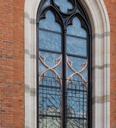 Zdjęcie nr 20: Kościół z cegły i kamienia. Na rzucie krzyża łacińskiego, jednonawowy z wciągniętymi do wnętrza przyporami. Prezbiterium krótkie, zamknięte pięcioma bokami ośmioboku. Korpus jednonawowy, czteroprzęsłowy, po bokach z płytkimi wnękami-kaplicami pomiędzy przyporami, poprzedzony od zach. przedsionkiem. Do pierwszego przęsła dostawione dwie symetryczne, trójboczne kaplice, nad nimi dwie czworoboczne wieże. Zakrystia przy prezbiterium na osi kościoła. Artykulacja ścian wnętrza za pomocą filarów opiętych półkolumnami z kapitelami z motywów liści. Między filarami rozpięte ostrołukowe arkady tworzące płytkie wnęki. Pierwsze przęsło wyróżnione przy pomocy masywnych filarów, ujętych niemal pełnoplastycznymi kolumnami. Okna ostrołukowe, dwudzielne z maswerkami, wsparte na gzymsach. Sklepienia krzyżowo-żebrowe na zaostrzonych gurtach. Kaplice artykułowane analogicznie do nawy kościoła, ze sklepieniami gwiaździstymi. Przedsionek otwiera się do kościoła trzema portalami ostrołukowymi opiętymi kolumnami. W polach archiwolt płaskorzeźby: Boże Narodzenie, Ukrzyżowanie, Wniebowstąpienie (K. Ceptowski).  W prezbiterium, na osi kościoła prostokątny otwór drzwiowy prowadzący do zakrystii. Chór muzyczny umieszczony nad kruchtą kościoła, na rzucie prostokąta, z kamienną balustradą maswerkową. Fasada kamienna, trójosiowa, zamknięta trójkątnie, flankowana lizenami przechodzącymi w ażurowe wieżyczki-latarnie, na rzucie kwadratu. Wieżyczki zwieńczone gzymsem i balustradą arkadową, hełmy ostrosłupowy zakończony iglicą. W dolnej części trzy filarowe arkady ostrołukowe, otwierające się do kruchty, sklepienie kruchty krzyżowo-żebrowe. Nad arkadami wejściowymi trzy tonda: litery IHS, Oko Opatrzności i splecione litery imienia Maria. Pośrodku na osi kościoła duża rozeta z maswerkiem, profilowana, otoczona pierścieniem wypełnionym stylizowanym ornamentem roślinnym. Ponad arkadami pełnoplastyczne figury czterech ewangelistów ustawionych na konsolach z rzeźbionymi atrybutami (F. Kuhn). Po bokach rozety prostokątne płyciny z traczami herbowymi Potockich i Branickich. U góry, na osi fasady figura Archanioła Michała. Elewacje na kamiennym cokole, z gzymsem kapnikowym, opięte prostokątnymi przyporami zwieńczonymi kamiennymi nakrywami. W górnej części kamienny fryz arkadkowy. Nad nim gzyms koronujący podtrzymujący ażurową, arkadową balustradę. Przy prezbiterium kaplice zamknięte trójbocznie, prezbiterium zamknięte pięciobocznie. Zakrystia na osi prezbiterium, na rzucie prostokąta, zwieńczona sygnaturką i ceglanym kominem. Po bokach prostokątne aneksy, południowy aneks - trzy okna ostrołukowe w kamiennej opasce, w środkowym przedstawienie Ukrzyżowanego Chrystusa. W północnym aneksie pojedyncze analogiczne okno. Okna ostrołukowe w profilowanych kamiennych opaskach, pomiędzy nimi a gzymsem koronującym mniejsze ostrołukowe w uskokowych arkadach. Nad kaplicami bocznymi dwie symetryczne wieże na rzucie kwadratu, w połowie wysokości kamienny gzyms z fryzem arkadkowym. Okna ostrołukowe w kamiennej opasce. Całość zwieńczona ślepym fryzem arkadkowym, wyżej gzyms dźwigający ażurową arkadkową balustradę. Hełmy ostrosłupowe, miedziane. Zakrystia na rzucie prostokąta, nakryta sklepieniem kolebkowym zaostrzonym i krzyżowym z lunetami , oddzielone gurtem. Portale od wschodu i zachodu prostokątne zamknięte łukiem ostrym. Okna ostrołukowe.