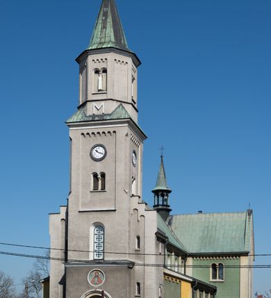 Zdjęcie nr 35: Budynki kościoła i plebanii znajdują się w centralnej części wsi, przy rynku na północ od głównej drogi z Krakowa do Oświęcimia. Kościół stoi przy obszernym placu, obwiedziony wysokim kamiennym murem z metalowym ogrodzeniem od południa. Kościół z prezbiterium zwróconym na północ, wzniesiony z kamienia wapiennego i cegły, tynkowany, z podmurówką. Świątynia wybudowana na planie krzyża łacińskiego z bazylikowym korpusem i transeptem. Dwuprzęsłowe prezbiterium zakończone półkoliście absydą zostało ujęte w dwa aneksy boczne, z których zachodni przeznaczony jest na zakrystię. Od południa do budynku przylega kruchta w przyziemiu wieży. Wnętrze kościoła trójnawowe, czteroprzęsłowe. Nawa główna łączy się z nawami bocznymi arkadami wspartymi na pięciobocznych filarach. Nawy boczne ujęte szerokimi pilastrami z pięciobocznymi filarami. Filary i pilastry stoją na wysokich, masywnych cokołach z kapitelami analogicznymi jak w nawie głównej. Ściany na skrzyżowaniu naw oraz ściany prezbiterium ujęte wspomnianymi filarami podtrzymującymi gurty sklepienia. Nawa i prezbiterium przykryte są sklepieniem kolebkowym z geometryzowanymi lunetami po obu stronach ścian. Ramiona transeptu sklepione kolebkowo z analogicznymi lunetami. Na skrzyżowaniu naw znajduje się sklepienie żaglaste. Nawę główną oświetlają rozmieszczone po jednym w każdym przęśle otwory okienne zamknięte łukiem półkolistym, okna w transepcie to biforia, widoczne tylko z zewnątrz okrągłe okno w absydzie wypełnione jest kamienną rozetą. Główne wejście od południa, do pierwszego przęsła od transeptu prowadzi dwoje drzwi w otworach o zamknięciu w kształcie łuku odciętego. W części zachodniej chór muzyczny wsparty na dwóch kolumnach i dwóch filarach dostawionych do ściany. Ich kapitele są analogiczne do pozostałych w kościele. Sklepienia dekorowane polichromią z rozetami i pękami lilii, a na skrzyżowaniu naw umieszczono malunek naścienny ukazujący Chrystusa tronującego z Bogiem Ojcem i gołębicą Ducha Świętego, a wokół nich cztery symbole ewangelistów. W fasadzie świątyni znajduje się strzelista wieża dwukondygnacyjna na planie czworokąta, przechodząca wyżej w ośmioboczną. Po bokach wieży wysokie aneksy zwieńczone schodkowo. Nad wejściem do kościoła znajduje się ozdobne okno zamknięte półkoliście i wypełnione czterema małymi rozetami ułożonymi jedna nad drugą. W kolejnej kondygnacji wieżę przepruwa biforium poniżej tarczy zegara i dekoracji arkadkowej. Wieża pełni jednocześnie funkcję dzwonnicy. Druga wieża na skrzyżowaniu nawy głównej i transeptu mieści sygnaturkę. Korpus kościoła nakryty dachem dwuspadowym, wieża wielobocznym. Wszystkie dachy kryte blachą.