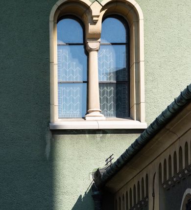 Zdjęcie nr 12: Budynki kościoła i plebanii znajdują się w centralnej części wsi, przy rynku na północ od głównej drogi z Krakowa do Oświęcimia. Kościół stoi przy obszernym placu, obwiedziony wysokim kamiennym murem z metalowym ogrodzeniem od południa. Kościół z prezbiterium zwróconym na północ, wzniesiony z kamienia wapiennego i cegły, tynkowany, z podmurówką. Świątynia wybudowana na planie krzyża łacińskiego z bazylikowym korpusem i transeptem. Dwuprzęsłowe prezbiterium zakończone półkoliście absydą zostało ujęte w dwa aneksy boczne, z których zachodni przeznaczony jest na zakrystię. Od południa do budynku przylega kruchta w przyziemiu wieży. Wnętrze kościoła trójnawowe, czteroprzęsłowe. Nawa główna łączy się z nawami bocznymi arkadami wspartymi na pięciobocznych filarach. Nawy boczne ujęte szerokimi pilastrami z pięciobocznymi filarami. Filary i pilastry stoją na wysokich, masywnych cokołach z kapitelami analogicznymi jak w nawie głównej. Ściany na skrzyżowaniu naw oraz ściany prezbiterium ujęte wspomnianymi filarami podtrzymującymi gurty sklepienia. Nawa i prezbiterium przykryte są sklepieniem kolebkowym z geometryzowanymi lunetami po obu stronach ścian. Ramiona transeptu sklepione kolebkowo z analogicznymi lunetami. Na skrzyżowaniu naw znajduje się sklepienie żaglaste. Nawę główną oświetlają rozmieszczone po jednym w każdym przęśle otwory okienne zamknięte łukiem półkolistym, okna w transepcie to biforia, widoczne tylko z zewnątrz okrągłe okno w absydzie wypełnione jest kamienną rozetą. Główne wejście od południa, do pierwszego przęsła od transeptu prowadzi dwoje drzwi w otworach o zamknięciu w kształcie łuku odciętego. W części zachodniej chór muzyczny wsparty na dwóch kolumnach i dwóch filarach dostawionych do ściany. Ich kapitele są analogiczne do pozostałych w kościele. Sklepienia dekorowane polichromią z rozetami i pękami lilii, a na skrzyżowaniu naw umieszczono malunek naścienny ukazujący Chrystusa tronującego z Bogiem Ojcem i gołębicą Ducha Świętego, a wokół nich cztery symbole ewangelistów. W fasadzie świątyni znajduje się strzelista wieża dwukondygnacyjna na planie czworokąta, przechodząca wyżej w ośmioboczną. Po bokach wieży wysokie aneksy zwieńczone schodkowo. Nad wejściem do kościoła znajduje się ozdobne okno zamknięte półkoliście i wypełnione czterema małymi rozetami ułożonymi jedna nad drugą. W kolejnej kondygnacji wieżę przepruwa biforium poniżej tarczy zegara i dekoracji arkadkowej. Wieża pełni jednocześnie funkcję dzwonnicy. Druga wieża na skrzyżowaniu nawy głównej i transeptu mieści sygnaturkę. Korpus kościoła nakryty dachem dwuspadowym, wieża wielobocznym. Wszystkie dachy kryte blachą.