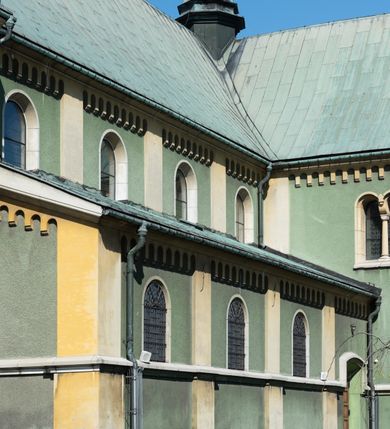 Zdjęcie nr 4: Budynki kościoła i plebanii znajdują się w centralnej części wsi, przy rynku na północ od głównej drogi z Krakowa do Oświęcimia. Kościół stoi przy obszernym placu, obwiedziony wysokim kamiennym murem z metalowym ogrodzeniem od południa. Kościół z prezbiterium zwróconym na północ, wzniesiony z kamienia wapiennego i cegły, tynkowany, z podmurówką. Świątynia wybudowana na planie krzyża łacińskiego z bazylikowym korpusem i transeptem. Dwuprzęsłowe prezbiterium zakończone półkoliście absydą zostało ujęte w dwa aneksy boczne, z których zachodni przeznaczony jest na zakrystię. Od południa do budynku przylega kruchta w przyziemiu wieży. Wnętrze kościoła trójnawowe, czteroprzęsłowe. Nawa główna łączy się z nawami bocznymi arkadami wspartymi na pięciobocznych filarach. Nawy boczne ujęte szerokimi pilastrami z pięciobocznymi filarami. Filary i pilastry stoją na wysokich, masywnych cokołach z kapitelami analogicznymi jak w nawie głównej. Ściany na skrzyżowaniu naw oraz ściany prezbiterium ujęte wspomnianymi filarami podtrzymującymi gurty sklepienia. Nawa i prezbiterium przykryte są sklepieniem kolebkowym z geometryzowanymi lunetami po obu stronach ścian. Ramiona transeptu sklepione kolebkowo z analogicznymi lunetami. Na skrzyżowaniu naw znajduje się sklepienie żaglaste. Nawę główną oświetlają rozmieszczone po jednym w każdym przęśle otwory okienne zamknięte łukiem półkolistym, okna w transepcie to biforia, widoczne tylko z zewnątrz okrągłe okno w absydzie wypełnione jest kamienną rozetą. Główne wejście od południa, do pierwszego przęsła od transeptu prowadzi dwoje drzwi w otworach o zamknięciu w kształcie łuku odciętego. W części zachodniej chór muzyczny wsparty na dwóch kolumnach i dwóch filarach dostawionych do ściany. Ich kapitele są analogiczne do pozostałych w kościele. Sklepienia dekorowane polichromią z rozetami i pękami lilii, a na skrzyżowaniu naw umieszczono malunek naścienny ukazujący Chrystusa tronującego z Bogiem Ojcem i gołębicą Ducha Świętego, a wokół nich cztery symbole ewangelistów. W fasadzie świątyni znajduje się strzelista wieża dwukondygnacyjna na planie czworokąta, przechodząca wyżej w ośmioboczną. Po bokach wieży wysokie aneksy zwieńczone schodkowo. Nad wejściem do kościoła znajduje się ozdobne okno zamknięte półkoliście i wypełnione czterema małymi rozetami ułożonymi jedna nad drugą. W kolejnej kondygnacji wieżę przepruwa biforium poniżej tarczy zegara i dekoracji arkadkowej. Wieża pełni jednocześnie funkcję dzwonnicy. Druga wieża na skrzyżowaniu nawy głównej i transeptu mieści sygnaturkę. Korpus kościoła nakryty dachem dwuspadowym, wieża wielobocznym. Wszystkie dachy kryte blachą.