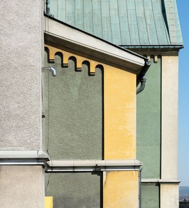 Zdjęcie nr 5: Budynki kościoła i plebanii znajdują się w centralnej części wsi, przy rynku na północ od głównej drogi z Krakowa do Oświęcimia. Kościół stoi przy obszernym placu, obwiedziony wysokim kamiennym murem z metalowym ogrodzeniem od południa. Kościół z prezbiterium zwróconym na północ, wzniesiony z kamienia wapiennego i cegły, tynkowany, z podmurówką. Świątynia wybudowana na planie krzyża łacińskiego z bazylikowym korpusem i transeptem. Dwuprzęsłowe prezbiterium zakończone półkoliście absydą zostało ujęte w dwa aneksy boczne, z których zachodni przeznaczony jest na zakrystię. Od południa do budynku przylega kruchta w przyziemiu wieży. Wnętrze kościoła trójnawowe, czteroprzęsłowe. Nawa główna łączy się z nawami bocznymi arkadami wspartymi na pięciobocznych filarach. Nawy boczne ujęte szerokimi pilastrami z pięciobocznymi filarami. Filary i pilastry stoją na wysokich, masywnych cokołach z kapitelami analogicznymi jak w nawie głównej. Ściany na skrzyżowaniu naw oraz ściany prezbiterium ujęte wspomnianymi filarami podtrzymującymi gurty sklepienia. Nawa i prezbiterium przykryte są sklepieniem kolebkowym z geometryzowanymi lunetami po obu stronach ścian. Ramiona transeptu sklepione kolebkowo z analogicznymi lunetami. Na skrzyżowaniu naw znajduje się sklepienie żaglaste. Nawę główną oświetlają rozmieszczone po jednym w każdym przęśle otwory okienne zamknięte łukiem półkolistym, okna w transepcie to biforia, widoczne tylko z zewnątrz okrągłe okno w absydzie wypełnione jest kamienną rozetą. Główne wejście od południa, do pierwszego przęsła od transeptu prowadzi dwoje drzwi w otworach o zamknięciu w kształcie łuku odciętego. W części zachodniej chór muzyczny wsparty na dwóch kolumnach i dwóch filarach dostawionych do ściany. Ich kapitele są analogiczne do pozostałych w kościele. Sklepienia dekorowane polichromią z rozetami i pękami lilii, a na skrzyżowaniu naw umieszczono malunek naścienny ukazujący Chrystusa tronującego z Bogiem Ojcem i gołębicą Ducha Świętego, a wokół nich cztery symbole ewangelistów. W fasadzie świątyni znajduje się strzelista wieża dwukondygnacyjna na planie czworokąta, przechodząca wyżej w ośmioboczną. Po bokach wieży wysokie aneksy zwieńczone schodkowo. Nad wejściem do kościoła znajduje się ozdobne okno zamknięte półkoliście i wypełnione czterema małymi rozetami ułożonymi jedna nad drugą. W kolejnej kondygnacji wieżę przepruwa biforium poniżej tarczy zegara i dekoracji arkadkowej. Wieża pełni jednocześnie funkcję dzwonnicy. Druga wieża na skrzyżowaniu nawy głównej i transeptu mieści sygnaturkę. Korpus kościoła nakryty dachem dwuspadowym, wieża wielobocznym. Wszystkie dachy kryte blachą.