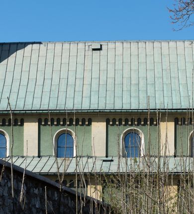 Zdjęcie nr 3: Budynki kościoła i plebanii znajdują się w centralnej części wsi, przy rynku na północ od głównej drogi z Krakowa do Oświęcimia. Kościół stoi przy obszernym placu, obwiedziony wysokim kamiennym murem z metalowym ogrodzeniem od południa. Kościół z prezbiterium zwróconym na północ, wzniesiony z kamienia wapiennego i cegły, tynkowany, z podmurówką. Świątynia wybudowana na planie krzyża łacińskiego z bazylikowym korpusem i transeptem. Dwuprzęsłowe prezbiterium zakończone półkoliście absydą zostało ujęte w dwa aneksy boczne, z których zachodni przeznaczony jest na zakrystię. Od południa do budynku przylega kruchta w przyziemiu wieży. Wnętrze kościoła trójnawowe, czteroprzęsłowe. Nawa główna łączy się z nawami bocznymi arkadami wspartymi na pięciobocznych filarach. Nawy boczne ujęte szerokimi pilastrami z pięciobocznymi filarami. Filary i pilastry stoją na wysokich, masywnych cokołach z kapitelami analogicznymi jak w nawie głównej. Ściany na skrzyżowaniu naw oraz ściany prezbiterium ujęte wspomnianymi filarami podtrzymującymi gurty sklepienia. Nawa i prezbiterium przykryte są sklepieniem kolebkowym z geometryzowanymi lunetami po obu stronach ścian. Ramiona transeptu sklepione kolebkowo z analogicznymi lunetami. Na skrzyżowaniu naw znajduje się sklepienie żaglaste. Nawę główną oświetlają rozmieszczone po jednym w każdym przęśle otwory okienne zamknięte łukiem półkolistym, okna w transepcie to biforia, widoczne tylko z zewnątrz okrągłe okno w absydzie wypełnione jest kamienną rozetą. Główne wejście od południa, do pierwszego przęsła od transeptu prowadzi dwoje drzwi w otworach o zamknięciu w kształcie łuku odciętego. W części zachodniej chór muzyczny wsparty na dwóch kolumnach i dwóch filarach dostawionych do ściany. Ich kapitele są analogiczne do pozostałych w kościele. Sklepienia dekorowane polichromią z rozetami i pękami lilii, a na skrzyżowaniu naw umieszczono malunek naścienny ukazujący Chrystusa tronującego z Bogiem Ojcem i gołębicą Ducha Świętego, a wokół nich cztery symbole ewangelistów. W fasadzie świątyni znajduje się strzelista wieża dwukondygnacyjna na planie czworokąta, przechodząca wyżej w ośmioboczną. Po bokach wieży wysokie aneksy zwieńczone schodkowo. Nad wejściem do kościoła znajduje się ozdobne okno zamknięte półkoliście i wypełnione czterema małymi rozetami ułożonymi jedna nad drugą. W kolejnej kondygnacji wieżę przepruwa biforium poniżej tarczy zegara i dekoracji arkadkowej. Wieża pełni jednocześnie funkcję dzwonnicy. Druga wieża na skrzyżowaniu nawy głównej i transeptu mieści sygnaturkę. Korpus kościoła nakryty dachem dwuspadowym, wieża wielobocznym. Wszystkie dachy kryte blachą.