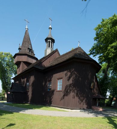 Zdjęcie nr 4: Kościół św. Jakuba w Palczowicach został wybudowany w roku 1894 w miejsce wcześniejszego kościoła z roku 1498. Kościół halowy, na kamiennej podmurówce, wzniesiony z drewna.  Kościół jest jednonawowy, orientowany.  Po jego zachodniej stronie szeroka, czworoboczna wieża nakryta ośmiobocznym hełmem. Pod hełmem również ośmioboczny szeroki, drewniany kandelabr. Hełm strzelisty, kryty gontem, zwieńczony metalowym krzyżem. Z czterech stron hełmu metalowe wykusze okienne  ze stylizowanymi sterczynami. Po czterech stronach korpusu wieży w jego wysokości małe otwory okienne  zwieńczone ostrokątnie. Korpus halowy nakryty dwuspadowym dachem z gontu.  We wschodniej części dachu ośmioboczna metalowa sygnaturka również zwieńczona krzyżem. Jej hełm strzelisty z pokryciem metalowym. W korpusie od południa i północy po dwa prostokątne otwory okienne z bliźniaczymi zamkniętymi ostrołukowo kwaterami. Prezbiterium niższe i węższe w stosunku do nawy, kryte osobnym, dwuspadowym dachem gontowym, zamknięte trójbocznie. Po południowej stronie prezbiterium dwa otwory okienne analogiczne do zlokalizowanych w nawie. Po północnej stronie prezbiterium dobudowana murowana, tynkowana zakrystia z dachem jednospadowym, krytym blachą.  W zakrystii jeden czworokątny otwór okienny i osobne wejście po stronie wschodniej. Nad głównym wejściem do kościoła, z czworobocznymi, dwuskrzydłowymi drzwiami  wysunięte dwuspadowe zadaszenie Po bokach drzwi w połowie ich wysokości symetrycznie ułożone, czworokątne otwory okienne. Do południowej ściany nawy głównej przylegająca drewniana kruchta na planie prostokątnym z dwuspadowym zadaszeniem zwieńczonym krzyżem. Po obu stronach drzwi otwory okienne zwieńczone ostrokątnie.