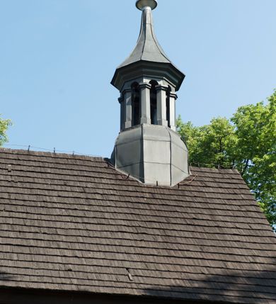 Zdjęcie nr 5: Kościół św. Jakuba w Palczowicach został wybudowany w roku 1894 w miejsce wcześniejszego kościoła z roku 1498. Kościół halowy, na kamiennej podmurówce, wzniesiony z drewna.  Kościół jest jednonawowy, orientowany.  Po jego zachodniej stronie szeroka, czworoboczna wieża nakryta ośmiobocznym hełmem. Pod hełmem również ośmioboczny szeroki, drewniany kandelabr. Hełm strzelisty, kryty gontem, zwieńczony metalowym krzyżem. Z czterech stron hełmu metalowe wykusze okienne  ze stylizowanymi sterczynami. Po czterech stronach korpusu wieży w jego wysokości małe otwory okienne  zwieńczone ostrokątnie. Korpus halowy nakryty dwuspadowym dachem z gontu.  We wschodniej części dachu ośmioboczna metalowa sygnaturka również zwieńczona krzyżem. Jej hełm strzelisty z pokryciem metalowym. W korpusie od południa i północy po dwa prostokątne otwory okienne z bliźniaczymi zamkniętymi ostrołukowo kwaterami. Prezbiterium niższe i węższe w stosunku do nawy, kryte osobnym, dwuspadowym dachem gontowym, zamknięte trójbocznie. Po południowej stronie prezbiterium dwa otwory okienne analogiczne do zlokalizowanych w nawie. Po północnej stronie prezbiterium dobudowana murowana, tynkowana zakrystia z dachem jednospadowym, krytym blachą.  W zakrystii jeden czworokątny otwór okienny i osobne wejście po stronie wschodniej. Nad głównym wejściem do kościoła, z czworobocznymi, dwuskrzydłowymi drzwiami  wysunięte dwuspadowe zadaszenie Po bokach drzwi w połowie ich wysokości symetrycznie ułożone, czworokątne otwory okienne. Do południowej ściany nawy głównej przylegająca drewniana kruchta na planie prostokątnym z dwuspadowym zadaszeniem zwieńczonym krzyżem. Po obu stronach drzwi otwory okienne zwieńczone ostrokątnie.