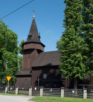 Zdjęcie nr 1: Kościół św. Jakuba w Palczowicach został wybudowany w roku 1894 w miejsce wcześniejszego kościoła z roku 1498. Kościół halowy, na kamiennej podmurówce, wzniesiony z drewna.  Kościół jest jednonawowy, orientowany.  Po jego zachodniej stronie szeroka, czworoboczna wieża nakryta ośmiobocznym hełmem. Pod hełmem również ośmioboczny szeroki, drewniany kandelabr. Hełm strzelisty, kryty gontem, zwieńczony metalowym krzyżem. Z czterech stron hełmu metalowe wykusze okienne  ze stylizowanymi sterczynami. Po czterech stronach korpusu wieży w jego wysokości małe otwory okienne  zwieńczone ostrokątnie. Korpus halowy nakryty dwuspadowym dachem z gontu.  We wschodniej części dachu ośmioboczna metalowa sygnaturka również zwieńczona krzyżem. Jej hełm strzelisty z pokryciem metalowym. W korpusie od południa i północy po dwa prostokątne otwory okienne z bliźniaczymi zamkniętymi ostrołukowo kwaterami. Prezbiterium niższe i węższe w stosunku do nawy, kryte osobnym, dwuspadowym dachem gontowym, zamknięte trójbocznie. Po południowej stronie prezbiterium dwa otwory okienne analogiczne do zlokalizowanych w nawie. Po północnej stronie prezbiterium dobudowana murowana, tynkowana zakrystia z dachem jednospadowym, krytym blachą.  W zakrystii jeden czworokątny otwór okienny i osobne wejście po stronie wschodniej. Nad głównym wejściem do kościoła, z czworobocznymi, dwuskrzydłowymi drzwiami  wysunięte dwuspadowe zadaszenie Po bokach drzwi w połowie ich wysokości symetrycznie ułożone, czworokątne otwory okienne. Do południowej ściany nawy głównej przylegająca drewniana kruchta na planie prostokątnym z dwuspadowym zadaszeniem zwieńczonym krzyżem. Po obu stronach drzwi otwory okienne zwieńczone ostrokątnie.