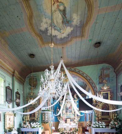 Zdjęcie nr 13: Kościół św. Jakuba w Palczowicach został wybudowany w roku 1894 w miejsce wcześniejszego kościoła z roku 1498. Kościół halowy, na kamiennej podmurówce, wzniesiony z drewna.  Kościół jest jednonawowy, orientowany.  Po jego zachodniej stronie szeroka, czworoboczna wieża nakryta ośmiobocznym hełmem. Pod hełmem również ośmioboczny szeroki, drewniany kandelabr. Hełm strzelisty, kryty gontem, zwieńczony metalowym krzyżem. Z czterech stron hełmu metalowe wykusze okienne  ze stylizowanymi sterczynami. Po czterech stronach korpusu wieży w jego wysokości małe otwory okienne  zwieńczone ostrokątnie. Korpus halowy nakryty dwuspadowym dachem z gontu.  We wschodniej części dachu ośmioboczna metalowa sygnaturka również zwieńczona krzyżem. Jej hełm strzelisty z pokryciem metalowym. W korpusie od południa i północy po dwa prostokątne otwory okienne z bliźniaczymi zamkniętymi ostrołukowo kwaterami. Prezbiterium niższe i węższe w stosunku do nawy, kryte osobnym, dwuspadowym dachem gontowym, zamknięte trójbocznie. Po południowej stronie prezbiterium dwa otwory okienne analogiczne do zlokalizowanych w nawie. Po północnej stronie prezbiterium dobudowana murowana, tynkowana zakrystia z dachem jednospadowym, krytym blachą.  W zakrystii jeden czworokątny otwór okienny i osobne wejście po stronie wschodniej. Nad głównym wejściem do kościoła, z czworobocznymi, dwuskrzydłowymi drzwiami  wysunięte dwuspadowe zadaszenie Po bokach drzwi w połowie ich wysokości symetrycznie ułożone, czworokątne otwory okienne. Do południowej ściany nawy głównej przylegająca drewniana kruchta na planie prostokątnym z dwuspadowym zadaszeniem zwieńczonym krzyżem. Po obu stronach drzwi otwory okienne zwieńczone ostrokątnie.