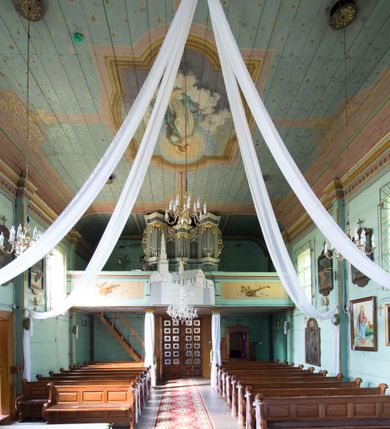 Zdjęcie nr 11: Kościół św. Jakuba w Palczowicach został wybudowany w roku 1894 w miejsce wcześniejszego kościoła z roku 1498. Kościół halowy, na kamiennej podmurówce, wzniesiony z drewna.  Kościół jest jednonawowy, orientowany.  Po jego zachodniej stronie szeroka, czworoboczna wieża nakryta ośmiobocznym hełmem. Pod hełmem również ośmioboczny szeroki, drewniany kandelabr. Hełm strzelisty, kryty gontem, zwieńczony metalowym krzyżem. Z czterech stron hełmu metalowe wykusze okienne  ze stylizowanymi sterczynami. Po czterech stronach korpusu wieży w jego wysokości małe otwory okienne  zwieńczone ostrokątnie. Korpus halowy nakryty dwuspadowym dachem z gontu.  We wschodniej części dachu ośmioboczna metalowa sygnaturka również zwieńczona krzyżem. Jej hełm strzelisty z pokryciem metalowym. W korpusie od południa i północy po dwa prostokątne otwory okienne z bliźniaczymi zamkniętymi ostrołukowo kwaterami. Prezbiterium niższe i węższe w stosunku do nawy, kryte osobnym, dwuspadowym dachem gontowym, zamknięte trójbocznie. Po południowej stronie prezbiterium dwa otwory okienne analogiczne do zlokalizowanych w nawie. Po północnej stronie prezbiterium dobudowana murowana, tynkowana zakrystia z dachem jednospadowym, krytym blachą.  W zakrystii jeden czworokątny otwór okienny i osobne wejście po stronie wschodniej. Nad głównym wejściem do kościoła, z czworobocznymi, dwuskrzydłowymi drzwiami  wysunięte dwuspadowe zadaszenie Po bokach drzwi w połowie ich wysokości symetrycznie ułożone, czworokątne otwory okienne. Do południowej ściany nawy głównej przylegająca drewniana kruchta na planie prostokątnym z dwuspadowym zadaszeniem zwieńczonym krzyżem. Po obu stronach drzwi otwory okienne zwieńczone ostrokątnie.