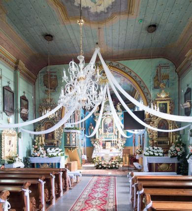 Zdjęcie nr 17: Kościół św. Jakuba w Palczowicach został wybudowany w roku 1894 w miejsce wcześniejszego kościoła z roku 1498. Kościół halowy, na kamiennej podmurówce, wzniesiony z drewna.  Kościół jest jednonawowy, orientowany.  Po jego zachodniej stronie szeroka, czworoboczna wieża nakryta ośmiobocznym hełmem. Pod hełmem również ośmioboczny szeroki, drewniany kandelabr. Hełm strzelisty, kryty gontem, zwieńczony metalowym krzyżem. Z czterech stron hełmu metalowe wykusze okienne  ze stylizowanymi sterczynami. Po czterech stronach korpusu wieży w jego wysokości małe otwory okienne  zwieńczone ostrokątnie. Korpus halowy nakryty dwuspadowym dachem z gontu.  We wschodniej części dachu ośmioboczna metalowa sygnaturka również zwieńczona krzyżem. Jej hełm strzelisty z pokryciem metalowym. W korpusie od południa i północy po dwa prostokątne otwory okienne z bliźniaczymi zamkniętymi ostrołukowo kwaterami. Prezbiterium niższe i węższe w stosunku do nawy, kryte osobnym, dwuspadowym dachem gontowym, zamknięte trójbocznie. Po południowej stronie prezbiterium dwa otwory okienne analogiczne do zlokalizowanych w nawie. Po północnej stronie prezbiterium dobudowana murowana, tynkowana zakrystia z dachem jednospadowym, krytym blachą.  W zakrystii jeden czworokątny otwór okienny i osobne wejście po stronie wschodniej. Nad głównym wejściem do kościoła, z czworobocznymi, dwuskrzydłowymi drzwiami  wysunięte dwuspadowe zadaszenie Po bokach drzwi w połowie ich wysokości symetrycznie ułożone, czworokątne otwory okienne. Do południowej ściany nawy głównej przylegająca drewniana kruchta na planie prostokątnym z dwuspadowym zadaszeniem zwieńczonym krzyżem. Po obu stronach drzwi otwory okienne zwieńczone ostrokątnie.