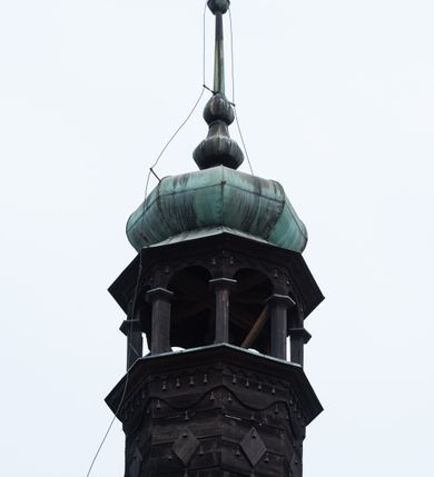 Zdjęcie nr 4: Dzwonnica na planie kwadratu do połowy wysokości murowana, wyżej drewniana, zwieńczona baniastym hełmem z latarnią. 
Część murowana nieco szersza. Od strony wschodniej znajdują się drzwi wejściowe, naroża są wzmocnione lizenami, od północy i południa znajdują się okna prostokątne zamknięte łukiem półokrągłym. Kondygnacje oddziela szeroki fartuch. Górna partia z pozorną izbicą przeprutą z każdej strony dwoma niewielkimi oknami w kształcie stojącego prostokąta zamkniętego łukiem pełnym. Od strony południowej otwór drzwiowy prostokątny zamknięty łukiem półokrągłym. Hełm baniasty przechodzi w oktogon,  na którym są arkadki wspierające mniejszy hełm cebulasty zwieńczony krzyżem. Dachy kryte blachą. 
