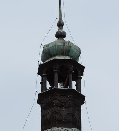 Zdjęcie nr 6: Dzwonnica na planie kwadratu do połowy wysokości murowana, wyżej drewniana, zwieńczona baniastym hełmem z latarnią. 
Część murowana nieco szersza. Od strony wschodniej znajdują się drzwi wejściowe, naroża są wzmocnione lizenami, od północy i południa znajdują się okna prostokątne zamknięte łukiem półokrągłym. Kondygnacje oddziela szeroki fartuch. Górna partia z pozorną izbicą przeprutą z każdej strony dwoma niewielkimi oknami w kształcie stojącego prostokąta zamkniętego łukiem pełnym. Od strony południowej otwór drzwiowy prostokątny zamknięty łukiem półokrągłym. Hełm baniasty przechodzi w oktogon,  na którym są arkadki wspierające mniejszy hełm cebulasty zwieńczony krzyżem. Dachy kryte blachą. 
