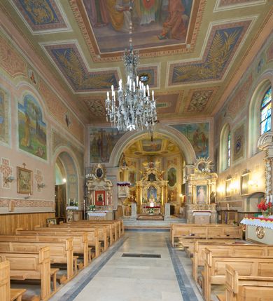 Zdjęcie nr 30: Kościół murowany, tynkowany, orientowany, jednonawowy. Prezbiterium prostokątne, krótkie, zamknięte trójbocznie, przy północnej ścianie prostokątna zakrystia z niższym przedsionkiem. Od wschodu, na zewnętrznej ścianie prezbiterium ogrójec. Nawa główna szersza od prezbiterium, na rzucie prostokąta, od północy przylega prostokątna kaplica, do której od zachodu dobudowany jest niski przedsionek, od południa przylega kruchta boczna, od zachodu prostokątny przedsionek z wieżą na planie kwadratu. Prezbiterium i nawa nakryte stropami, łuk tęczowy półkolisty, wewnątrz ujęty pilastrami, zakończony kluczem. Dostęp do kaplicy z nawy głównej przez wysokie przejście arkadowe na ścianie północnej, w południowej przejście do kruchty bocznej, na osi, pod chórem wejście do przedsionka. Kaplica boczna sklepiona kolebkowo. Fasada bez podziałów z wbudowaną wieżą, ujętą spłaszczonymi spływami. Na osi portal wejściowy flankowany dwoma pilastrami podtrzymującymi gzyms, na którym znajduje się półkoliste okno. W polu dwuskrzydłowe drzwi wejściowe ujęte opaską tynkową. Wieża dwukondygnacyjna, w dolnej kondygnacji okulus, w górnej okna w formie stojącego prostokąta zamkniętego łukiem półkolistym usytuowane z czterech stron. Na spływach ujmujących wieżę dwa okulusy. Wieża nakryta dachem ostrosłupowym. Południowa ściana oraz prezbiterium opięte grubymi szkarpami nakrytymi daszkami o nieregularnej wysokości. Do wschodniej ściany prezbiterium dobudowany murowany ogrojec flankowany filarami, nakryty wielospadowym daszkiem. Elewacje gładkie, tynkowane zakończone profilowanym gzymsem. Wejścia do kościoła przez przybudówkę kaplicy bocznej od północy oraz przez zachodni przedsionek i południową kruchtę. Okna w formie stojącego prostokąta zamkniętego łukiem półkolistym: siedem w elewacji południowej, trzy w północnej. Okna w formie stojącego prostokąta w dwóch kondygnacjach na północnej i południowej ścianie przedsionka zachodniego. Nawa główna, prezbiterium, kaplica i kruchta boczna nakryte dachem dwuspadowym, zakrystia i przybudówki dachami pulpitowymi. 
