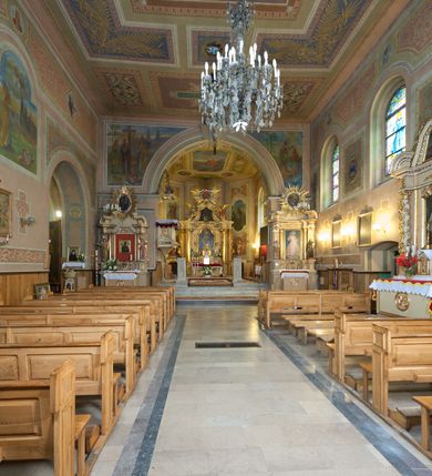 Zdjęcie nr 25: Kościół murowany, tynkowany, orientowany, jednonawowy. Prezbiterium prostokątne, krótkie, zamknięte trójbocznie, przy północnej ścianie prostokątna zakrystia z niższym przedsionkiem. Od wschodu, na zewnętrznej ścianie prezbiterium ogrójec. Nawa główna szersza od prezbiterium, na rzucie prostokąta, od północy przylega prostokątna kaplica, do której od zachodu dobudowany jest niski przedsionek, od południa przylega kruchta boczna, od zachodu prostokątny przedsionek z wieżą na planie kwadratu. Prezbiterium i nawa nakryte stropami, łuk tęczowy półkolisty, wewnątrz ujęty pilastrami, zakończony kluczem. Dostęp do kaplicy z nawy głównej przez wysokie przejście arkadowe na ścianie północnej, w południowej przejście do kruchty bocznej, na osi, pod chórem wejście do przedsionka. Kaplica boczna sklepiona kolebkowo. Fasada bez podziałów z wbudowaną wieżą, ujętą spłaszczonymi spływami. Na osi portal wejściowy flankowany dwoma pilastrami podtrzymującymi gzyms, na którym znajduje się półkoliste okno. W polu dwuskrzydłowe drzwi wejściowe ujęte opaską tynkową. Wieża dwukondygnacyjna, w dolnej kondygnacji okulus, w górnej okna w formie stojącego prostokąta zamkniętego łukiem półkolistym usytuowane z czterech stron. Na spływach ujmujących wieżę dwa okulusy. Wieża nakryta dachem ostrosłupowym. Południowa ściana oraz prezbiterium opięte grubymi szkarpami nakrytymi daszkami o nieregularnej wysokości. Do wschodniej ściany prezbiterium dobudowany murowany ogrojec flankowany filarami, nakryty wielospadowym daszkiem. Elewacje gładkie, tynkowane zakończone profilowanym gzymsem. Wejścia do kościoła przez przybudówkę kaplicy bocznej od północy oraz przez zachodni przedsionek i południową kruchtę. Okna w formie stojącego prostokąta zamkniętego łukiem półkolistym: siedem w elewacji południowej, trzy w północnej. Okna w formie stojącego prostokąta w dwóch kondygnacjach na północnej i południowej ścianie przedsionka zachodniego. Nawa główna, prezbiterium, kaplica i kruchta boczna nakryte dachem dwuspadowym, zakrystia i przybudówki dachami pulpitowymi. 
