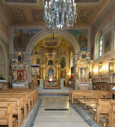 Zdjęcie nr 31: Kościół murowany, tynkowany, orientowany, jednonawowy. Prezbiterium prostokątne, krótkie, zamknięte trójbocznie, przy północnej ścianie prostokątna zakrystia z niższym przedsionkiem. Od wschodu, na zewnętrznej ścianie prezbiterium ogrójec. Nawa główna szersza od prezbiterium, na rzucie prostokąta, od północy przylega prostokątna kaplica, do której od zachodu dobudowany jest niski przedsionek, od południa przylega kruchta boczna, od zachodu prostokątny przedsionek z wieżą na planie kwadratu. Prezbiterium i nawa nakryte stropami, łuk tęczowy półkolisty, wewnątrz ujęty pilastrami, zakończony kluczem. Dostęp do kaplicy z nawy głównej przez wysokie przejście arkadowe na ścianie północnej, w południowej przejście do kruchty bocznej, na osi, pod chórem wejście do przedsionka. Kaplica boczna sklepiona kolebkowo. Fasada bez podziałów z wbudowaną wieżą, ujętą spłaszczonymi spływami. Na osi portal wejściowy flankowany dwoma pilastrami podtrzymującymi gzyms, na którym znajduje się półkoliste okno. W polu dwuskrzydłowe drzwi wejściowe ujęte opaską tynkową. Wieża dwukondygnacyjna, w dolnej kondygnacji okulus, w górnej okna w formie stojącego prostokąta zamkniętego łukiem półkolistym usytuowane z czterech stron. Na spływach ujmujących wieżę dwa okulusy. Wieża nakryta dachem ostrosłupowym. Południowa ściana oraz prezbiterium opięte grubymi szkarpami nakrytymi daszkami o nieregularnej wysokości. Do wschodniej ściany prezbiterium dobudowany murowany ogrojec flankowany filarami, nakryty wielospadowym daszkiem. Elewacje gładkie, tynkowane zakończone profilowanym gzymsem. Wejścia do kościoła przez przybudówkę kaplicy bocznej od północy oraz przez zachodni przedsionek i południową kruchtę. Okna w formie stojącego prostokąta zamkniętego łukiem półkolistym: siedem w elewacji południowej, trzy w północnej. Okna w formie stojącego prostokąta w dwóch kondygnacjach na północnej i południowej ścianie przedsionka zachodniego. Nawa główna, prezbiterium, kaplica i kruchta boczna nakryte dachem dwuspadowym, zakrystia i przybudówki dachami pulpitowymi. 
