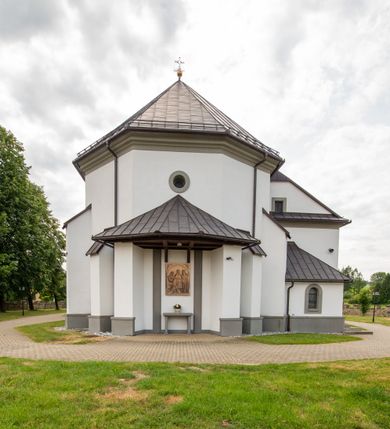 Zdjęcie nr 16: Kościół murowany, tynkowany, orientowany, jednonawowy. Prezbiterium prostokątne, krótkie, zamknięte trójbocznie, przy północnej ścianie prostokątna zakrystia z niższym przedsionkiem. Od wschodu, na zewnętrznej ścianie prezbiterium ogrójec. Nawa główna szersza od prezbiterium, na rzucie prostokąta, od północy przylega prostokątna kaplica, do której od zachodu dobudowany jest niski przedsionek, od południa przylega kruchta boczna, od zachodu prostokątny przedsionek z wieżą na planie kwadratu. Prezbiterium i nawa nakryte stropami, łuk tęczowy półkolisty, wewnątrz ujęty pilastrami, zakończony kluczem. Dostęp do kaplicy z nawy głównej przez wysokie przejście arkadowe na ścianie północnej, w południowej przejście do kruchty bocznej, na osi, pod chórem wejście do przedsionka. Kaplica boczna sklepiona kolebkowo. Fasada bez podziałów z wbudowaną wieżą, ujętą spłaszczonymi spływami. Na osi portal wejściowy flankowany dwoma pilastrami podtrzymującymi gzyms, na którym znajduje się półkoliste okno. W polu dwuskrzydłowe drzwi wejściowe ujęte opaską tynkową. Wieża dwukondygnacyjna, w dolnej kondygnacji okulus, w górnej okna w formie stojącego prostokąta zamkniętego łukiem półkolistym usytuowane z czterech stron. Na spływach ujmujących wieżę dwa okulusy. Wieża nakryta dachem ostrosłupowym. Południowa ściana oraz prezbiterium opięte grubymi szkarpami nakrytymi daszkami o nieregularnej wysokości. Do wschodniej ściany prezbiterium dobudowany murowany ogrojec flankowany filarami, nakryty wielospadowym daszkiem. Elewacje gładkie, tynkowane zakończone profilowanym gzymsem. Wejścia do kościoła przez przybudówkę kaplicy bocznej od północy oraz przez zachodni przedsionek i południową kruchtę. Okna w formie stojącego prostokąta zamkniętego łukiem półkolistym: siedem w elewacji południowej, trzy w północnej. Okna w formie stojącego prostokąta w dwóch kondygnacjach na północnej i południowej ścianie przedsionka zachodniego. Nawa główna, prezbiterium, kaplica i kruchta boczna nakryte dachem dwuspadowym, zakrystia i przybudówki dachami pulpitowymi. 
