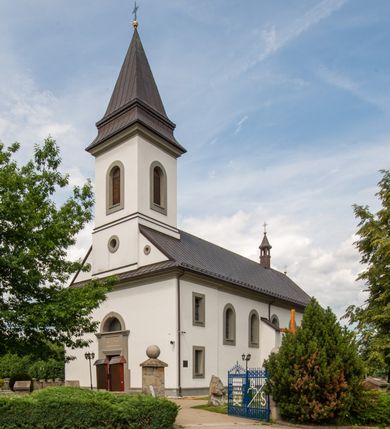 Zdjęcie nr 22: Kościół murowany, tynkowany, orientowany, jednonawowy. Prezbiterium prostokątne, krótkie, zamknięte trójbocznie, przy północnej ścianie prostokątna zakrystia z niższym przedsionkiem. Od wschodu, na zewnętrznej ścianie prezbiterium ogrójec. Nawa główna szersza od prezbiterium, na rzucie prostokąta, od północy przylega prostokątna kaplica, do której od zachodu dobudowany jest niski przedsionek, od południa przylega kruchta boczna, od zachodu prostokątny przedsionek z wieżą na planie kwadratu. Prezbiterium i nawa nakryte stropami, łuk tęczowy półkolisty, wewnątrz ujęty pilastrami, zakończony kluczem. Dostęp do kaplicy z nawy głównej przez wysokie przejście arkadowe na ścianie północnej, w południowej przejście do kruchty bocznej, na osi, pod chórem wejście do przedsionka. Kaplica boczna sklepiona kolebkowo. Fasada bez podziałów z wbudowaną wieżą, ujętą spłaszczonymi spływami. Na osi portal wejściowy flankowany dwoma pilastrami podtrzymującymi gzyms, na którym znajduje się półkoliste okno. W polu dwuskrzydłowe drzwi wejściowe ujęte opaską tynkową. Wieża dwukondygnacyjna, w dolnej kondygnacji okulus, w górnej okna w formie stojącego prostokąta zamkniętego łukiem półkolistym usytuowane z czterech stron. Na spływach ujmujących wieżę dwa okulusy. Wieża nakryta dachem ostrosłupowym. Południowa ściana oraz prezbiterium opięte grubymi szkarpami nakrytymi daszkami o nieregularnej wysokości. Do wschodniej ściany prezbiterium dobudowany murowany ogrojec flankowany filarami, nakryty wielospadowym daszkiem. Elewacje gładkie, tynkowane zakończone profilowanym gzymsem. Wejścia do kościoła przez przybudówkę kaplicy bocznej od północy oraz przez zachodni przedsionek i południową kruchtę. Okna w formie stojącego prostokąta zamkniętego łukiem półkolistym: siedem w elewacji południowej, trzy w północnej. Okna w formie stojącego prostokąta w dwóch kondygnacjach na północnej i południowej ścianie przedsionka zachodniego. Nawa główna, prezbiterium, kaplica i kruchta boczna nakryte dachem dwuspadowym, zakrystia i przybudówki dachami pulpitowymi. 
