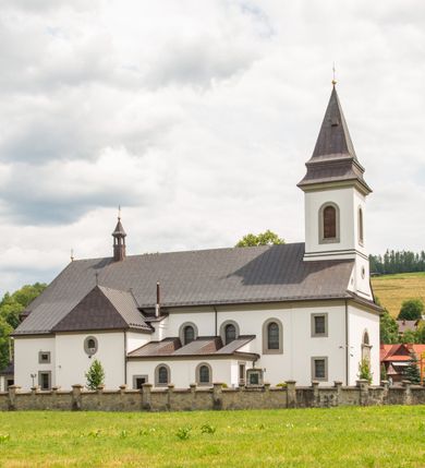 Zdjęcie nr 6: Kościół murowany, tynkowany, orientowany, jednonawowy. Prezbiterium prostokątne, krótkie, zamknięte trójbocznie, przy północnej ścianie prostokątna zakrystia z niższym przedsionkiem. Od wschodu, na zewnętrznej ścianie prezbiterium ogrójec. Nawa główna szersza od prezbiterium, na rzucie prostokąta, od północy przylega prostokątna kaplica, do której od zachodu dobudowany jest niski przedsionek, od południa przylega kruchta boczna, od zachodu prostokątny przedsionek z wieżą na planie kwadratu. Prezbiterium i nawa nakryte stropami, łuk tęczowy półkolisty, wewnątrz ujęty pilastrami, zakończony kluczem. Dostęp do kaplicy z nawy głównej przez wysokie przejście arkadowe na ścianie północnej, w południowej przejście do kruchty bocznej, na osi, pod chórem wejście do przedsionka. Kaplica boczna sklepiona kolebkowo. Fasada bez podziałów z wbudowaną wieżą, ujętą spłaszczonymi spływami. Na osi portal wejściowy flankowany dwoma pilastrami podtrzymującymi gzyms, na którym znajduje się półkoliste okno. W polu dwuskrzydłowe drzwi wejściowe ujęte opaską tynkową. Wieża dwukondygnacyjna, w dolnej kondygnacji okulus, w górnej okna w formie stojącego prostokąta zamkniętego łukiem półkolistym usytuowane z czterech stron. Na spływach ujmujących wieżę dwa okulusy. Wieża nakryta dachem ostrosłupowym. Południowa ściana oraz prezbiterium opięte grubymi szkarpami nakrytymi daszkami o nieregularnej wysokości. Do wschodniej ściany prezbiterium dobudowany murowany ogrojec flankowany filarami, nakryty wielospadowym daszkiem. Elewacje gładkie, tynkowane zakończone profilowanym gzymsem. Wejścia do kościoła przez przybudówkę kaplicy bocznej od północy oraz przez zachodni przedsionek i południową kruchtę. Okna w formie stojącego prostokąta zamkniętego łukiem półkolistym: siedem w elewacji południowej, trzy w północnej. Okna w formie stojącego prostokąta w dwóch kondygnacjach na północnej i południowej ścianie przedsionka zachodniego. Nawa główna, prezbiterium, kaplica i kruchta boczna nakryte dachem dwuspadowym, zakrystia i przybudówki dachami pulpitowymi. 
