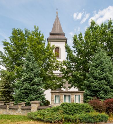 Zdjęcie nr 10: Kościół murowany, tynkowany, orientowany, jednonawowy. Prezbiterium prostokątne, krótkie, zamknięte trójbocznie, przy północnej ścianie prostokątna zakrystia z niższym przedsionkiem. Od wschodu, na zewnętrznej ścianie prezbiterium ogrójec. Nawa główna szersza od prezbiterium, na rzucie prostokąta, od północy przylega prostokątna kaplica, do której od zachodu dobudowany jest niski przedsionek, od południa przylega kruchta boczna, od zachodu prostokątny przedsionek z wieżą na planie kwadratu. Prezbiterium i nawa nakryte stropami, łuk tęczowy półkolisty, wewnątrz ujęty pilastrami, zakończony kluczem. Dostęp do kaplicy z nawy głównej przez wysokie przejście arkadowe na ścianie północnej, w południowej przejście do kruchty bocznej, na osi, pod chórem wejście do przedsionka. Kaplica boczna sklepiona kolebkowo. Fasada bez podziałów z wbudowaną wieżą, ujętą spłaszczonymi spływami. Na osi portal wejściowy flankowany dwoma pilastrami podtrzymującymi gzyms, na którym znajduje się półkoliste okno. W polu dwuskrzydłowe drzwi wejściowe ujęte opaską tynkową. Wieża dwukondygnacyjna, w dolnej kondygnacji okulus, w górnej okna w formie stojącego prostokąta zamkniętego łukiem półkolistym usytuowane z czterech stron. Na spływach ujmujących wieżę dwa okulusy. Wieża nakryta dachem ostrosłupowym. Południowa ściana oraz prezbiterium opięte grubymi szkarpami nakrytymi daszkami o nieregularnej wysokości. Do wschodniej ściany prezbiterium dobudowany murowany ogrojec flankowany filarami, nakryty wielospadowym daszkiem. Elewacje gładkie, tynkowane zakończone profilowanym gzymsem. Wejścia do kościoła przez przybudówkę kaplicy bocznej od północy oraz przez zachodni przedsionek i południową kruchtę. Okna w formie stojącego prostokąta zamkniętego łukiem półkolistym: siedem w elewacji południowej, trzy w północnej. Okna w formie stojącego prostokąta w dwóch kondygnacjach na północnej i południowej ścianie przedsionka zachodniego. Nawa główna, prezbiterium, kaplica i kruchta boczna nakryte dachem dwuspadowym, zakrystia i przybudówki dachami pulpitowymi. 
