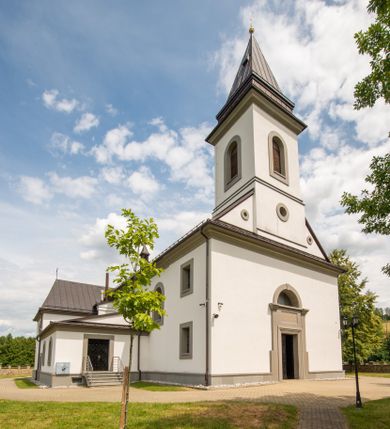Zdjęcie nr 1: Kościół murowany, tynkowany, orientowany, jednonawowy. Prezbiterium prostokątne, krótkie, zamknięte trójbocznie, przy północnej ścianie prostokątna zakrystia z niższym przedsionkiem. Od wschodu, na zewnętrznej ścianie prezbiterium ogrójec. Nawa główna szersza od prezbiterium, na rzucie prostokąta, od północy przylega prostokątna kaplica, do której od zachodu dobudowany jest niski przedsionek, od południa przylega kruchta boczna, od zachodu prostokątny przedsionek z wieżą na planie kwadratu. Prezbiterium i nawa nakryte stropami, łuk tęczowy półkolisty, wewnątrz ujęty pilastrami, zakończony kluczem. Dostęp do kaplicy z nawy głównej przez wysokie przejście arkadowe na ścianie północnej, w południowej przejście do kruchty bocznej, na osi, pod chórem wejście do przedsionka. Kaplica boczna sklepiona kolebkowo. Fasada bez podziałów z wbudowaną wieżą, ujętą spłaszczonymi spływami. Na osi portal wejściowy flankowany dwoma pilastrami podtrzymującymi gzyms, na którym znajduje się półkoliste okno. W polu dwuskrzydłowe drzwi wejściowe ujęte opaską tynkową. Wieża dwukondygnacyjna, w dolnej kondygnacji okulus, w górnej okna w formie stojącego prostokąta zamkniętego łukiem półkolistym usytuowane z czterech stron. Na spływach ujmujących wieżę dwa okulusy. Wieża nakryta dachem ostrosłupowym. Południowa ściana oraz prezbiterium opięte grubymi szkarpami nakrytymi daszkami o nieregularnej wysokości. Do wschodniej ściany prezbiterium dobudowany murowany ogrojec flankowany filarami, nakryty wielospadowym daszkiem. Elewacje gładkie, tynkowane zakończone profilowanym gzymsem. Wejścia do kościoła przez przybudówkę kaplicy bocznej od północy oraz przez zachodni przedsionek i południową kruchtę. Okna w formie stojącego prostokąta zamkniętego łukiem półkolistym: siedem w elewacji południowej, trzy w północnej. Okna w formie stojącego prostokąta w dwóch kondygnacjach na północnej i południowej ścianie przedsionka zachodniego. Nawa główna, prezbiterium, kaplica i kruchta boczna nakryte dachem dwuspadowym, zakrystia i przybudówki dachami pulpitowymi. 
