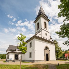 Zdjęcie nr 1: Kościół murowany, tynkowany, orientowany, jednonawowy. Prezbiterium prostokątne, krótkie, zamknięte trójbocznie, przy północnej ścianie prostokątna zakrystia z niższym przedsionkiem. Od wschodu, na zewnętrznej ścianie prezbiterium ogrójec. Nawa główna szersza od prezbiterium, na rzucie prostokąta, od północy przylega prostokątna kaplica, do której od zachodu dobudowany jest niski przedsionek, od południa przylega kruchta boczna, od zachodu prostokątny przedsionek z wieżą na planie kwadratu. Prezbiterium i nawa nakryte stropami, łuk tęczowy półkolisty, wewnątrz ujęty pilastrami, zakończony kluczem. Dostęp do kaplicy z nawy głównej przez wysokie przejście arkadowe na ścianie północnej, w południowej przejście do kruchty bocznej, na osi, pod chórem wejście do przedsionka. Kaplica boczna sklepiona kolebkowo. Fasada bez podziałów z wbudowaną wieżą, ujętą spłaszczonymi spływami. Na osi portal wejściowy flankowany dwoma pilastrami podtrzymującymi gzyms, na którym znajduje się półkoliste okno. W polu dwuskrzydłowe drzwi wejściowe ujęte opaską tynkową. Wieża dwukondygnacyjna, w dolnej kondygnacji okulus, w górnej okna w formie stojącego prostokąta zamkniętego łukiem półkolistym usytuowane z czterech stron. Na spływach ujmujących wieżę dwa okulusy. Wieża nakryta dachem ostrosłupowym. Południowa ściana oraz prezbiterium opięte grubymi szkarpami nakrytymi daszkami o nieregularnej wysokości. Do wschodniej ściany prezbiterium dobudowany murowany ogrojec flankowany filarami, nakryty wielospadowym daszkiem. Elewacje gładkie, tynkowane zakończone profilowanym gzymsem. Wejścia do kościoła przez przybudówkę kaplicy bocznej od północy oraz przez zachodni przedsionek i południową kruchtę. Okna w formie stojącego prostokąta zamkniętego łukiem półkolistym: siedem w elewacji południowej, trzy w północnej. Okna w formie stojącego prostokąta w dwóch kondygnacjach na północnej i południowej ścianie przedsionka zachodniego. Nawa główna, prezbiterium, kaplica i kruchta boczna nakryte dachem dwuspadowym, zakrystia i przybudówki dachami pulpitowymi. 
