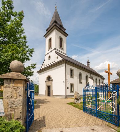 Zdjęcie nr 9: Kościół murowany, tynkowany, orientowany, jednonawowy. Prezbiterium prostokątne, krótkie, zamknięte trójbocznie, przy północnej ścianie prostokątna zakrystia z niższym przedsionkiem. Od wschodu, na zewnętrznej ścianie prezbiterium ogrójec. Nawa główna szersza od prezbiterium, na rzucie prostokąta, od północy przylega prostokątna kaplica, do której od zachodu dobudowany jest niski przedsionek, od południa przylega kruchta boczna, od zachodu prostokątny przedsionek z wieżą na planie kwadratu. Prezbiterium i nawa nakryte stropami, łuk tęczowy półkolisty, wewnątrz ujęty pilastrami, zakończony kluczem. Dostęp do kaplicy z nawy głównej przez wysokie przejście arkadowe na ścianie północnej, w południowej przejście do kruchty bocznej, na osi, pod chórem wejście do przedsionka. Kaplica boczna sklepiona kolebkowo. Fasada bez podziałów z wbudowaną wieżą, ujętą spłaszczonymi spływami. Na osi portal wejściowy flankowany dwoma pilastrami podtrzymującymi gzyms, na którym znajduje się półkoliste okno. W polu dwuskrzydłowe drzwi wejściowe ujęte opaską tynkową. Wieża dwukondygnacyjna, w dolnej kondygnacji okulus, w górnej okna w formie stojącego prostokąta zamkniętego łukiem półkolistym usytuowane z czterech stron. Na spływach ujmujących wieżę dwa okulusy. Wieża nakryta dachem ostrosłupowym. Południowa ściana oraz prezbiterium opięte grubymi szkarpami nakrytymi daszkami o nieregularnej wysokości. Do wschodniej ściany prezbiterium dobudowany murowany ogrojec flankowany filarami, nakryty wielospadowym daszkiem. Elewacje gładkie, tynkowane zakończone profilowanym gzymsem. Wejścia do kościoła przez przybudówkę kaplicy bocznej od północy oraz przez zachodni przedsionek i południową kruchtę. Okna w formie stojącego prostokąta zamkniętego łukiem półkolistym: siedem w elewacji południowej, trzy w północnej. Okna w formie stojącego prostokąta w dwóch kondygnacjach na północnej i południowej ścianie przedsionka zachodniego. Nawa główna, prezbiterium, kaplica i kruchta boczna nakryte dachem dwuspadowym, zakrystia i przybudówki dachami pulpitowymi. 
