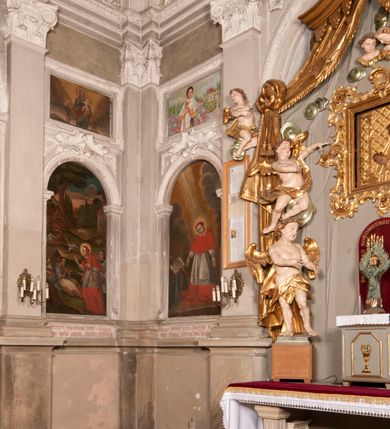 Zdjęcie nr 126: Kaplica zbudowana została na planie kwadratu i nakryta wzniesioną na pendentywach kopułą z latarnią. Przylega do kościoła od północy, do pierwszego przęsła nawy, z którą komunikuje się zamkniętym półkoliście przejściem. Wnętrze artykułowane jest w oparciu o schemat starożytnego łuku triumfalnego za pomocą osadzonych na wysokim cokole pilastrów z kompozytowymi głowicami. Pilastry podtrzymują wydatne belkowanie, ozodbione dekoracją stiukową w postaci puttów, festonów owocowych, rozet oraz kartuszy. Równocześnie pilastry ujmują półkoliste arkady, dwie niższe i większą, środkową. Niższe arkady wypełniają obrazy ze scenami z życia św. Karola Boromeusza. Ponad nimi w prostokątnych, stiukowych, obramieniach znajdują się malowane przedstawienia różnych świętych. W środkowej arkadzie ściany północnej umieszczono okazały późnobarokowy ołtarz z cudownym wizerunkiem św. Karola Boromeusza. Z kolei w arkadach wschodniej i zachodniej rozmieszczono prostokątne okna. Poniżej okna w arkadzie zachodniej znajduje się wyjście na zewnątrz kaplicy zaopatrzone w metalowe, prostokątne drzwi. Natomiast pod oknem w ścianie wschodniej zawieszono tablicę pamiątkową ku czci papieża Jana Pawła II. Arkadę wejściową do kaplicy zamyka prostokątna, brązowa krata. W jej podłuczu od wnętrza na wzór tympanonu umieszczono stiukowy kartusz z herbem Szreniawa, podtrzymywany przez dwa anioły. Ściany tarczowe podniebia przepruto czworobocznymi oknami ujętymi w stiukowe obramienia wolutowe. Na pendentywach przedstawiono w czterech stiukowych kartuszach herby: Szreniawa, Gryf i Kotwicz. Czwarty kartusz jest pusty. Czaszę kopuły wypełnia iluzjonistycznie malowana architektura podzielona na dwie strefy. Dolną artykułują pary pilastrów ujmujące okulusy oraz tralkowa balustrada, a górną gurty wyznaczające pola dla dekoracji ornamentalnej. Ściany zewnętrzne kaplicy zostały podzielone za pomocą kamiennych gzymsów i lizen na dwie trójosiowe kondygnacje, z których górna odpowiada wysokością smukłemu cokołowi mieszczącemu wejście. Zewnętrzne pola każdej elewacji dekorowane są płaskimi pasami tynku w układzie wzoru geometrycznego, zbliżonego do okuciowego. Okna i portal zostały ujęte w profilowane kamienne obramienia. Na ścianie północnej w środkowej kondygnacji pod kartuszem z herbem Szreniawa umieszczono tablicę fundacyjną z napisem: STANISLAUS COMES IN WIŚNICZ LUBOMIRSKI / PALATINUS ET GENERALIS CRACOVIEN[SIS] / SCEPUSIEN[SIS], BIALLOCERKIEVIEN[SIS] / ZATHORIEN[SIS], NIEPOLOMICIEN[SIS] E[T]C[ETER]A, E[T]C[ETER]A, CAPITANEUS / CAPELLAM HANC, / S[ANCTO] CAROLO BARRHOMAEO SUO TUTELARI PATRONO / POST RECEPTA SA[N]CTI HUIUS MERITIS TOT BENEFICIA / DICATAM / EX FUNDAMENTIS EREXIT, DONAVIT / EXORNAVIT, / ANNO D[O]MI[NI], 1640 (Stanisław hrabia na Wiśniczu Lubomirski wojewoda i starosta generalny krakowski, starosta spiski, białocerkiewski, zatorski, niepołomicki, i tak dalej, i tak dalej, tę kaplicę, poświęconą św. Karolowi Boromeuszowi, swojemu patronowi opiekuńczemu, po otrzymaniu tak wielkich łask za wstawiennictwem tego świetego, od fundamentów wzniósł, uposażył i ozdobił, roku Pańskiego 1640). Dach kaplicy oraz latarnia pokryte są blachą miedzianą.

