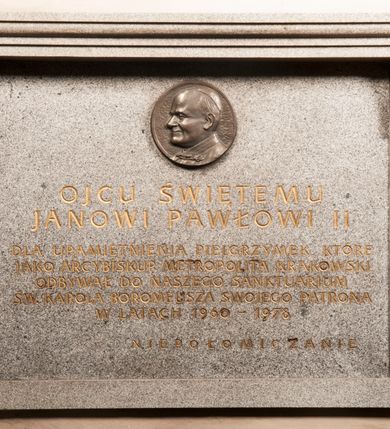 Zdjęcie nr 135: Kaplica zbudowana została na planie kwadratu i nakryta wzniesioną na pendentywach kopułą z latarnią. Przylega do kościoła od północy, do pierwszego przęsła nawy, z którą komunikuje się zamkniętym półkoliście przejściem. Wnętrze artykułowane jest w oparciu o schemat starożytnego łuku triumfalnego za pomocą osadzonych na wysokim cokole pilastrów z kompozytowymi głowicami. Pilastry podtrzymują wydatne belkowanie, ozodbione dekoracją stiukową w postaci puttów, festonów owocowych, rozet oraz kartuszy. Równocześnie pilastry ujmują półkoliste arkady, dwie niższe i większą, środkową. Niższe arkady wypełniają obrazy ze scenami z życia św. Karola Boromeusza. Ponad nimi w prostokątnych, stiukowych, obramieniach znajdują się malowane przedstawienia różnych świętych. W środkowej arkadzie ściany północnej umieszczono okazały późnobarokowy ołtarz z cudownym wizerunkiem św. Karola Boromeusza. Z kolei w arkadach wschodniej i zachodniej rozmieszczono prostokątne okna. Poniżej okna w arkadzie zachodniej znajduje się wyjście na zewnątrz kaplicy zaopatrzone w metalowe, prostokątne drzwi. Natomiast pod oknem w ścianie wschodniej zawieszono tablicę pamiątkową ku czci papieża Jana Pawła II. Arkadę wejściową do kaplicy zamyka prostokątna, brązowa krata. W jej podłuczu od wnętrza na wzór tympanonu umieszczono stiukowy kartusz z herbem Szreniawa, podtrzymywany przez dwa anioły. Ściany tarczowe podniebia przepruto czworobocznymi oknami ujętymi w stiukowe obramienia wolutowe. Na pendentywach przedstawiono w czterech stiukowych kartuszach herby: Szreniawa, Gryf i Kotwicz. Czwarty kartusz jest pusty. Czaszę kopuły wypełnia iluzjonistycznie malowana architektura podzielona na dwie strefy. Dolną artykułują pary pilastrów ujmujące okulusy oraz tralkowa balustrada, a górną gurty wyznaczające pola dla dekoracji ornamentalnej. Ściany zewnętrzne kaplicy zostały podzielone za pomocą kamiennych gzymsów i lizen na dwie trójosiowe kondygnacje, z których górna odpowiada wysokością smukłemu cokołowi mieszczącemu wejście. Zewnętrzne pola każdej elewacji dekorowane są płaskimi pasami tynku w układzie wzoru geometrycznego, zbliżonego do okuciowego. Okna i portal zostały ujęte w profilowane kamienne obramienia. Na ścianie północnej w środkowej kondygnacji pod kartuszem z herbem Szreniawa umieszczono tablicę fundacyjną z napisem: STANISLAUS COMES IN WIŚNICZ LUBOMIRSKI / PALATINUS ET GENERALIS CRACOVIEN[SIS] / SCEPUSIEN[SIS], BIALLOCERKIEVIEN[SIS] / ZATHORIEN[SIS], NIEPOLOMICIEN[SIS] E[T]C[ETER]A, E[T]C[ETER]A, CAPITANEUS / CAPELLAM HANC, / S[ANCTO] CAROLO BARRHOMAEO SUO TUTELARI PATRONO / POST RECEPTA SA[N]CTI HUIUS MERITIS TOT BENEFICIA / DICATAM / EX FUNDAMENTIS EREXIT, DONAVIT / EXORNAVIT, / ANNO D[O]MI[NI], 1640 (Stanisław hrabia na Wiśniczu Lubomirski wojewoda i starosta generalny krakowski, starosta spiski, białocerkiewski, zatorski, niepołomicki, i tak dalej, i tak dalej, tę kaplicę, poświęconą św. Karolowi Boromeuszowi, swojemu patronowi opiekuńczemu, po otrzymaniu tak wielkich łask za wstawiennictwem tego świetego, od fundamentów wzniósł, uposażył i ozdobił, roku Pańskiego 1640). Dach kaplicy oraz latarnia pokryte są blachą miedzianą.
