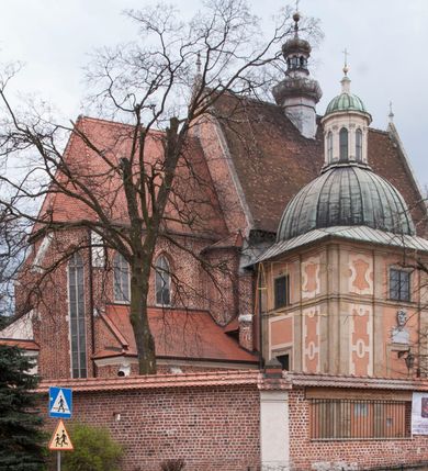 Zdjęcie nr 2: Kaplica zbudowana została na planie kwadratu i nakryta wzniesioną na pendentywach kopułą z latarnią. Przylega do kościoła od północy, do pierwszego przęsła nawy, z którą komunikuje się zamkniętym półkoliście przejściem. Wnętrze artykułowane jest w oparciu o schemat starożytnego łuku triumfalnego za pomocą osadzonych na wysokim cokole pilastrów z kompozytowymi głowicami. Pilastry podtrzymują wydatne belkowanie, ozodbione dekoracją stiukową w postaci puttów, festonów owocowych, rozet oraz kartuszy. Równocześnie pilastry ujmują półkoliste arkady, dwie niższe i większą, środkową. Niższe arkady wypełniają obrazy ze scenami z życia św. Karola Boromeusza. Ponad nimi w prostokątnych, stiukowych, obramieniach znajdują się malowane przedstawienia różnych świętych. W środkowej arkadzie ściany północnej umieszczono okazały późnobarokowy ołtarz z cudownym wizerunkiem św. Karola Boromeusza. Z kolei w arkadach wschodniej i zachodniej rozmieszczono prostokątne okna. Poniżej okna w arkadzie zachodniej znajduje się wyjście na zewnątrz kaplicy zaopatrzone w metalowe, prostokątne drzwi. Natomiast pod oknem w ścianie wschodniej zawieszono tablicę pamiątkową ku czci papieża Jana Pawła II. Arkadę wejściową do kaplicy zamyka prostokątna, brązowa krata. W jej podłuczu od wnętrza na wzór tympanonu umieszczono stiukowy kartusz z herbem Szreniawa, podtrzymywany przez dwa anioły. Ściany tarczowe podniebia przepruto czworobocznymi oknami ujętymi w stiukowe obramienia wolutowe. Na pendentywach przedstawiono w czterech stiukowych kartuszach herby: Szreniawa, Gryf i Kotwicz. Czwarty kartusz jest pusty. Czaszę kopuły wypełnia iluzjonistycznie malowana architektura podzielona na dwie strefy. Dolną artykułują pary pilastrów ujmujące okulusy oraz tralkowa balustrada, a górną gurty wyznaczające pola dla dekoracji ornamentalnej. Ściany zewnętrzne kaplicy zostały podzielone za pomocą kamiennych gzymsów i lizen na dwie trójosiowe kondygnacje, z których górna odpowiada wysokością smukłemu cokołowi mieszczącemu wejście. Zewnętrzne pola każdej elewacji dekorowane są płaskimi pasami tynku w układzie wzoru geometrycznego, zbliżonego do okuciowego. Okna i portal zostały ujęte w profilowane kamienne obramienia. Na ścianie północnej w środkowej kondygnacji pod kartuszem z herbem Szreniawa umieszczono tablicę fundacyjną z napisem: STANISLAUS COMES IN WIŚNICZ LUBOMIRSKI / PALATINUS ET GENERALIS CRACOVIEN[SIS] / SCEPUSIEN[SIS], BIALLOCERKIEVIEN[SIS] / ZATHORIEN[SIS], NIEPOLOMICIEN[SIS] E[T]C[ETER]A, E[T]C[ETER]A, CAPITANEUS / CAPELLAM HANC, / S[ANCTO] CAROLO BARRHOMAEO SUO TUTELARI PATRONO / POST RECEPTA SA[N]CTI HUIUS MERITIS TOT BENEFICIA / DICATAM / EX FUNDAMENTIS EREXIT, DONAVIT / EXORNAVIT, / ANNO D[O]MI[NI], 1640 (Stanisław hrabia na Wiśniczu Lubomirski wojewoda i starosta generalny krakowski, starosta spiski, białocerkiewski, zatorski, niepołomicki, i tak dalej, i tak dalej, tę kaplicę, poświęconą św. Karolowi Boromeuszowi, swojemu patronowi opiekuńczemu, po otrzymaniu tak wielkich łask za wstawiennictwem tego świetego, od fundamentów wzniósł, uposażył i ozdobił, roku Pańskiego 1640). Dach kaplicy oraz latarnia pokryte są blachą miedzianą.
