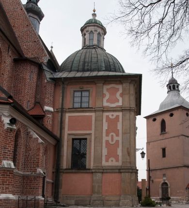 Zdjęcie nr 1: Kaplica zbudowana została na planie kwadratu i nakryta wzniesioną na pendentywach kopułą z latarnią. Przylega do kościoła od północy, do pierwszego przęsła nawy, z którą komunikuje się zamkniętym półkoliście przejściem. Wnętrze artykułowane jest w oparciu o schemat starożytnego łuku triumfalnego za pomocą osadzonych na wysokim cokole pilastrów z kompozytowymi głowicami. Pilastry podtrzymują wydatne belkowanie, ozodbione dekoracją stiukową w postaci puttów, festonów owocowych, rozet oraz kartuszy. Równocześnie pilastry ujmują półkoliste arkady, dwie niższe i większą, środkową. Niższe arkady wypełniają obrazy ze scenami z życia św. Karola Boromeusza. Ponad nimi w prostokątnych, stiukowych, obramieniach znajdują się malowane przedstawienia różnych świętych. W środkowej arkadzie ściany północnej umieszczono okazały późnobarokowy ołtarz z cudownym wizerunkiem św. Karola Boromeusza. Z kolei w arkadach wschodniej i zachodniej rozmieszczono prostokątne okna. Poniżej okna w arkadzie zachodniej znajduje się wyjście na zewnątrz kaplicy zaopatrzone w metalowe, prostokątne drzwi. Natomiast pod oknem w ścianie wschodniej zawieszono tablicę pamiątkową ku czci papieża Jana Pawła II. Arkadę wejściową do kaplicy zamyka prostokątna, brązowa krata. W jej podłuczu od wnętrza na wzór tympanonu umieszczono stiukowy kartusz z herbem Szreniawa, podtrzymywany przez dwa anioły. Ściany tarczowe podniebia przepruto czworobocznymi oknami ujętymi w stiukowe obramienia wolutowe. Na pendentywach przedstawiono w czterech stiukowych kartuszach herby: Szreniawa, Gryf i Kotwicz. Czwarty kartusz jest pusty. Czaszę kopuły wypełnia iluzjonistycznie malowana architektura podzielona na dwie strefy. Dolną artykułują pary pilastrów ujmujące okulusy oraz tralkowa balustrada, a górną gurty wyznaczające pola dla dekoracji ornamentalnej. Ściany zewnętrzne kaplicy zostały podzielone za pomocą kamiennych gzymsów i lizen na dwie trójosiowe kondygnacje, z których górna odpowiada wysokością smukłemu cokołowi mieszczącemu wejście. Zewnętrzne pola każdej elewacji dekorowane są płaskimi pasami tynku w układzie wzoru geometrycznego, zbliżonego do okuciowego. Okna i portal zostały ujęte w profilowane kamienne obramienia. Na ścianie północnej w środkowej kondygnacji pod kartuszem z herbem Szreniawa umieszczono tablicę fundacyjną z napisem: STANISLAUS COMES IN WIŚNICZ LUBOMIRSKI / PALATINUS ET GENERALIS CRACOVIEN[SIS] / SCEPUSIEN[SIS], BIALLOCERKIEVIEN[SIS] / ZATHORIEN[SIS], NIEPOLOMICIEN[SIS] E[T]C[ETER]A, E[T]C[ETER]A, CAPITANEUS / CAPELLAM HANC, / S[ANCTO] CAROLO BARRHOMAEO SUO TUTELARI PATRONO / POST RECEPTA SA[N]CTI HUIUS MERITIS TOT BENEFICIA / DICATAM / EX FUNDAMENTIS EREXIT, DONAVIT / EXORNAVIT, / ANNO D[O]MI[NI], 1640 (Stanisław hrabia na Wiśniczu Lubomirski wojewoda i starosta generalny krakowski, starosta spiski, białocerkiewski, zatorski, niepołomicki, i tak dalej, i tak dalej, tę kaplicę, poświęconą św. Karolowi Boromeuszowi, swojemu patronowi opiekuńczemu, po otrzymaniu tak wielkich łask za wstawiennictwem tego świetego, od fundamentów wzniósł, uposażył i ozdobił, roku Pańskiego 1640). Dach kaplicy oraz latarnia pokryte są blachą miedzianą.
