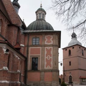 Zdjęcie nr 1: Kaplica zbudowana została na planie kwadratu i nakryta wzniesioną na pendentywach kopułą z latarnią. Przylega do kościoła od północy, do pierwszego przęsła nawy, z którą komunikuje się zamkniętym półkoliście przejściem. Wnętrze artykułowane jest w oparciu o schemat starożytnego łuku triumfalnego za pomocą osadzonych na wysokim cokole pilastrów z kompozytowymi głowicami. Pilastry podtrzymują wydatne belkowanie, ozodbione dekoracją stiukową w postaci puttów, festonów owocowych, rozet oraz kartuszy. Równocześnie pilastry ujmują półkoliste arkady, dwie niższe i większą, środkową. Niższe arkady wypełniają obrazy ze scenami z życia św. Karola Boromeusza. Ponad nimi w prostokątnych, stiukowych, obramieniach znajdują się malowane przedstawienia różnych świętych. W środkowej arkadzie ściany północnej umieszczono okazały późnobarokowy ołtarz z cudownym wizerunkiem św. Karola Boromeusza. Z kolei w arkadach wschodniej i zachodniej rozmieszczono prostokątne okna. Poniżej okna w arkadzie zachodniej znajduje się wyjście na zewnątrz kaplicy zaopatrzone w metalowe, prostokątne drzwi. Natomiast pod oknem w ścianie wschodniej zawieszono tablicę pamiątkową ku czci papieża Jana Pawła II. Arkadę wejściową do kaplicy zamyka prostokątna, brązowa krata. W jej podłuczu od wnętrza na wzór tympanonu umieszczono stiukowy kartusz z herbem Szreniawa, podtrzymywany przez dwa anioły. Ściany tarczowe podniebia przepruto czworobocznymi oknami ujętymi w stiukowe obramienia wolutowe. Na pendentywach przedstawiono w czterech stiukowych kartuszach herby: Szreniawa, Gryf i Kotwicz. Czwarty kartusz jest pusty. Czaszę kopuły wypełnia iluzjonistycznie malowana architektura podzielona na dwie strefy. Dolną artykułują pary pilastrów ujmujące okulusy oraz tralkowa balustrada, a górną gurty wyznaczające pola dla dekoracji ornamentalnej. Ściany zewnętrzne kaplicy zostały podzielone za pomocą kamiennych gzymsów i lizen na dwie trójosiowe kondygnacje, z których górna odpowiada wysokością smukłemu cokołowi mieszczącemu wejście. Zewnętrzne pola każdej elewacji dekorowane są płaskimi pasami tynku w układzie wzoru geometrycznego, zbliżonego do okuciowego. Okna i portal zostały ujęte w profilowane kamienne obramienia. Na ścianie północnej w środkowej kondygnacji pod kartuszem z herbem Szreniawa umieszczono tablicę fundacyjną z napisem: STANISLAUS COMES IN WIŚNICZ LUBOMIRSKI / PALATINUS ET GENERALIS CRACOVIEN[SIS] / SCEPUSIEN[SIS], BIALLOCERKIEVIEN[SIS] / ZATHORIEN[SIS], NIEPOLOMICIEN[SIS] E[T]C[ETER]A, E[T]C[ETER]A, CAPITANEUS / CAPELLAM HANC, / S[ANCTO] CAROLO BARRHOMAEO SUO TUTELARI PATRONO / POST RECEPTA SA[N]CTI HUIUS MERITIS TOT BENEFICIA / DICATAM / EX FUNDAMENTIS EREXIT, DONAVIT / EXORNAVIT, / ANNO D[O]MI[NI], 1640 (Stanisław hrabia na Wiśniczu Lubomirski wojewoda i starosta generalny krakowski, starosta spiski, białocerkiewski, zatorski, niepołomicki, i tak dalej, i tak dalej, tę kaplicę, poświęconą św. Karolowi Boromeuszowi, swojemu patronowi opiekuńczemu, po otrzymaniu tak wielkich łask za wstawiennictwem tego świetego, od fundamentów wzniósł, uposażył i ozdobił, roku Pańskiego 1640). Dach kaplicy oraz latarnia pokryte są blachą miedzianą.
