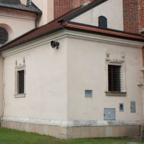 Zdjęcie nr 1: Zakrystia tzw. nowa zlokalizowana przy prezbiterium od południa, zbudowana z cegły, z użyciem ciosu kamiennego do detalu, na rzucie prostokąta Sklepienie kolebkowe z lunetami. Okna prostokątne, w kamiennych obramieniach z uszakami i sterczynami na nadprożach. Portal z prezbiterium do zakrystii kamienny, z herbem Śreniawa. Elewacje na cokole, z gzymsem koronującym profilowanym, tynkowane. Dach pulpitowy.  