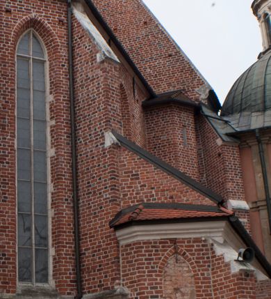 Zdjęcie nr 2: Kościół położony na południe od rynku, na placu otoczonym kamiennym murem z dwiema bramkami od zachodu i północy oraz bramką od południa. Kościół jednonawowy, dwuprzęsłowy, z węższym, niższym dwuprzęsłowym prezbiterium zamkniętym pięciobocznie. Do prezbiterium przylegają dwa aneksy, od północy dawna zakrystia (obecnie kaplica świętych Męczennic), zamknięta od wschodu dwubocznie, mająca w narożu z korpusem wieżyczkę schodową, a od południa zakrystia nowa, na planie prostokąta. Do nawy przylegają dwie kaplice: od północy kaplica Lubomirskich, założona na rzucie kwadratu, nakryta kopułą, a od południa kaplica Branickich, także na rzucie kwadratu z kopułą. Przy korpusie od zachodu piętrowa kruchta, pierwotnie otwarta w przyziemiu od północy, zachodu i południa ostrołukowymi arkadami. Arkada tęczy ostrołukowa. Sklepienie prezbiterium, zakrystii i obu kondygnacjach kruchty krzyżowo-żebrowe, w korpusie, pierwotnie trójprzęsłowym, pierwotnie sklepienie o polach trójkątnych z trójpromieniem, wsparte na dwóch dziesięciobocznych filarach, obecnie kolebkowo z lunetami. Żebra w prezbiterium i zakrystii o profilu żłobkowym, w kruchcie - gruszkowym. W prezbiterium służki cylindryczne, nadwieszone na oplecionych liśćmi wspornikach oraz rzeźbione zworniki z przedstawieniem Głowy Chrystusa i motywami roślinnymi. Ściany rozczłonkowane wykonanymi w czarnego marmuru arkadami, zamkniętymi łukiem półkolistymi. Okna ostrołukowe , obustronnie rozglifione z krzyżowym laskowaniem, w ścianie północnym prezbiterium ślepe. Kościół opięty przyporami. Elewacje na cokole, z profilowanymi gzymsami cokołowymi, kapnikowym i koronującym. Szczyty zwieńczone kwiatonami, z których zachodnie z krzyżem. Portale kamienne, ostrołukowe: zachodni profilowany, z ażurowym maswerkiem; drugi w prezbiterium do zakrystii, profilowany; trzeci do wieżyczki schodowej.