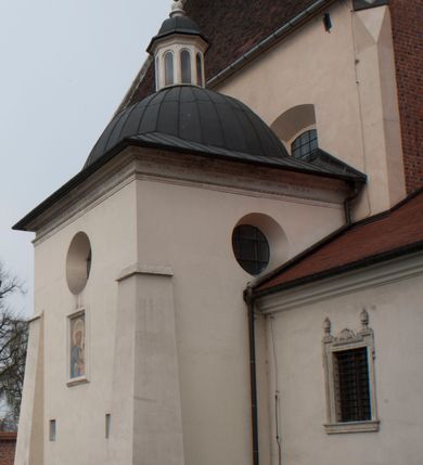 Zdjęcie nr 7: Kościół położony na południe od rynku, na placu otoczonym kamiennym murem z dwiema bramkami od zachodu i północy oraz bramką od południa. Kościół jednonawowy, dwuprzęsłowy, z węższym, niższym dwuprzęsłowym prezbiterium zamkniętym pięciobocznie. Do prezbiterium przylegają dwa aneksy, od północy dawna zakrystia (obecnie kaplica świętych Męczennic), zamknięta od wschodu dwubocznie, mająca w narożu z korpusem wieżyczkę schodową, a od południa zakrystia nowa, na planie prostokąta. Do nawy przylegają dwie kaplice: od północy kaplica Lubomirskich, założona na rzucie kwadratu, nakryta kopułą, a od południa kaplica Branickich, także na rzucie kwadratu z kopułą. Przy korpusie od zachodu piętrowa kruchta, pierwotnie otwarta w przyziemiu od północy, zachodu i południa ostrołukowymi arkadami. Arkada tęczy ostrołukowa. Sklepienie prezbiterium, zakrystii i obu kondygnacjach kruchty krzyżowo-żebrowe, w korpusie, pierwotnie trójprzęsłowym, pierwotnie sklepienie o polach trójkątnych z trójpromieniem, wsparte na dwóch dziesięciobocznych filarach, obecnie kolebkowo z lunetami. Żebra w prezbiterium i zakrystii o profilu żłobkowym, w kruchcie - gruszkowym. W prezbiterium służki cylindryczne, nadwieszone na oplecionych liśćmi wspornikach oraz rzeźbione zworniki z przedstawieniem Głowy Chrystusa i motywami roślinnymi. Ściany rozczłonkowane wykonanymi w czarnego marmuru arkadami, zamkniętymi łukiem półkolistymi. Okna ostrołukowe , obustronnie rozglifione z krzyżowym laskowaniem, w ścianie północnym prezbiterium ślepe. Kościół opięty przyporami. Elewacje na cokole, z profilowanymi gzymsami cokołowymi, kapnikowym i koronującym. Szczyty zwieńczone kwiatonami, z których zachodnie z krzyżem. Portale kamienne, ostrołukowe: zachodni profilowany, z ażurowym maswerkiem; drugi w prezbiterium do zakrystii, profilowany; trzeci do wieżyczki schodowej.