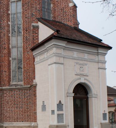 Zdjęcie nr 6: Kościół położony na południe od rynku, na placu otoczonym kamiennym murem z dwiema bramkami od zachodu i północy oraz bramką od południa. Kościół jednonawowy, dwuprzęsłowy, z węższym, niższym dwuprzęsłowym prezbiterium zamkniętym pięciobocznie. Do prezbiterium przylegają dwa aneksy, od północy dawna zakrystia (obecnie kaplica świętych Męczennic), zamknięta od wschodu dwubocznie, mająca w narożu z korpusem wieżyczkę schodową, a od południa zakrystia nowa, na planie prostokąta. Do nawy przylegają dwie kaplice: od północy kaplica Lubomirskich, założona na rzucie kwadratu, nakryta kopułą, a od południa kaplica Branickich, także na rzucie kwadratu z kopułą. Przy korpusie od zachodu piętrowa kruchta, pierwotnie otwarta w przyziemiu od północy, zachodu i południa ostrołukowymi arkadami. Arkada tęczy ostrołukowa. Sklepienie prezbiterium, zakrystii i obu kondygnacjach kruchty krzyżowo-żebrowe, w korpusie, pierwotnie trójprzęsłowym, pierwotnie sklepienie o polach trójkątnych z trójpromieniem, wsparte na dwóch dziesięciobocznych filarach, obecnie kolebkowo z lunetami. Żebra w prezbiterium i zakrystii o profilu żłobkowym, w kruchcie - gruszkowym. W prezbiterium służki cylindryczne, nadwieszone na oplecionych liśćmi wspornikach oraz rzeźbione zworniki z przedstawieniem Głowy Chrystusa i motywami roślinnymi. Ściany rozczłonkowane wykonanymi w czarnego marmuru arkadami, zamkniętymi łukiem półkolistymi. Okna ostrołukowe , obustronnie rozglifione z krzyżowym laskowaniem, w ścianie północnym prezbiterium ślepe. Kościół opięty przyporami. Elewacje na cokole, z profilowanymi gzymsami cokołowymi, kapnikowym i koronującym. Szczyty zwieńczone kwiatonami, z których zachodnie z krzyżem. Portale kamienne, ostrołukowe: zachodni profilowany, z ażurowym maswerkiem; drugi w prezbiterium do zakrystii, profilowany; trzeci do wieżyczki schodowej.