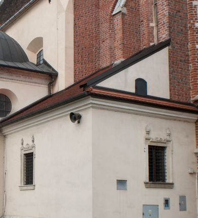 Zdjęcie nr 10: Kościół położony na południe od rynku, na placu otoczonym kamiennym murem z dwiema bramkami od zachodu i północy oraz bramką od południa. Kościół jednonawowy, dwuprzęsłowy, z węższym, niższym dwuprzęsłowym prezbiterium zamkniętym pięciobocznie. Do prezbiterium przylegają dwa aneksy, od północy dawna zakrystia (obecnie kaplica świętych Męczennic), zamknięta od wschodu dwubocznie, mająca w narożu z korpusem wieżyczkę schodową, a od południa zakrystia nowa, na planie prostokąta. Do nawy przylegają dwie kaplice: od północy kaplica Lubomirskich, założona na rzucie kwadratu, nakryta kopułą, a od południa kaplica Branickich, także na rzucie kwadratu z kopułą. Przy korpusie od zachodu piętrowa kruchta, pierwotnie otwarta w przyziemiu od północy, zachodu i południa ostrołukowymi arkadami. Arkada tęczy ostrołukowa. Sklepienie prezbiterium, zakrystii i obu kondygnacjach kruchty krzyżowo-żebrowe, w korpusie, pierwotnie trójprzęsłowym, pierwotnie sklepienie o polach trójkątnych z trójpromieniem, wsparte na dwóch dziesięciobocznych filarach, obecnie kolebkowo z lunetami. Żebra w prezbiterium i zakrystii o profilu żłobkowym, w kruchcie - gruszkowym. W prezbiterium służki cylindryczne, nadwieszone na oplecionych liśćmi wspornikach oraz rzeźbione zworniki z przedstawieniem Głowy Chrystusa i motywami roślinnymi. Ściany rozczłonkowane wykonanymi w czarnego marmuru arkadami, zamkniętymi łukiem półkolistymi. Okna ostrołukowe , obustronnie rozglifione z krzyżowym laskowaniem, w ścianie północnym prezbiterium ślepe. Kościół opięty przyporami. Elewacje na cokole, z profilowanymi gzymsami cokołowymi, kapnikowym i koronującym. Szczyty zwieńczone kwiatonami, z których zachodnie z krzyżem. Portale kamienne, ostrołukowe: zachodni profilowany, z ażurowym maswerkiem; drugi w prezbiterium do zakrystii, profilowany; trzeci do wieżyczki schodowej.