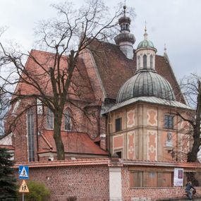 Zdjęcie nr 1: Kościół położony na południe od rynku, na placu otoczonym kamiennym murem z dwiema bramkami od zachodu i północy oraz bramką od południa. Kościół jednonawowy, dwuprzęsłowy, z węższym, niższym dwuprzęsłowym prezbiterium zamkniętym pięciobocznie. Do prezbiterium przylegają dwa aneksy, od północy dawna zakrystia (obecnie kaplica świętych Męczennic), zamknięta od wschodu dwubocznie, mająca w narożu z korpusem wieżyczkę schodową, a od południa zakrystia nowa, na planie prostokąta. Do nawy przylegają dwie kaplice: od północy kaplica Lubomirskich, założona na rzucie kwadratu, nakryta kopułą, a od południa kaplica Branickich, także na rzucie kwadratu z kopułą. Przy korpusie od zachodu piętrowa kruchta, pierwotnie otwarta w przyziemiu od północy, zachodu i południa ostrołukowymi arkadami. Arkada tęczy ostrołukowa. Sklepienie prezbiterium, zakrystii i obu kondygnacjach kruchty krzyżowo-żebrowe, w korpusie, pierwotnie trójprzęsłowym, pierwotnie sklepienie o polach trójkątnych z trójpromieniem, wsparte na dwóch dziesięciobocznych filarach, obecnie kolebkowo z lunetami. Żebra w prezbiterium i zakrystii o profilu żłobkowym, w kruchcie - gruszkowym. W prezbiterium służki cylindryczne, nadwieszone na oplecionych liśćmi wspornikach oraz rzeźbione zworniki z przedstawieniem Głowy Chrystusa i motywami roślinnymi. Ściany rozczłonkowane wykonanymi w czarnego marmuru arkadami, zamkniętymi łukiem półkolistymi. Okna ostrołukowe , obustronnie rozglifione z krzyżowym laskowaniem, w ścianie północnym prezbiterium ślepe. Kościół opięty przyporami. Elewacje na cokole, z profilowanymi gzymsami cokołowymi, kapnikowym i koronującym. Szczyty zwieńczone kwiatonami, z których zachodnie z krzyżem. Portale kamienne, ostrołukowe: zachodni profilowany, z ażurowym maswerkiem; drugi w prezbiterium do zakrystii, profilowany; trzeci do wieżyczki schodowej.