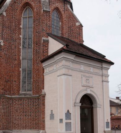Zdjęcie nr 3: Kościół położony na południe od rynku, na placu otoczonym kamiennym murem z dwiema bramkami od zachodu i północy oraz bramką od południa. Kościół jednonawowy, dwuprzęsłowy, z węższym, niższym dwuprzęsłowym prezbiterium zamkniętym pięciobocznie. Do prezbiterium przylegają dwa aneksy, od północy dawna zakrystia (obecnie kaplica świętych Męczennic), zamknięta od wschodu dwubocznie, mająca w narożu z korpusem wieżyczkę schodową, a od południa zakrystia nowa, na planie prostokąta. Do nawy przylegają dwie kaplice: od północy kaplica Lubomirskich, założona na rzucie kwadratu, nakryta kopułą, a od południa kaplica Branickich, także na rzucie kwadratu z kopułą. Przy korpusie od zachodu piętrowa kruchta, pierwotnie otwarta w przyziemiu od północy, zachodu i południa ostrołukowymi arkadami. Arkada tęczy ostrołukowa. Sklepienie prezbiterium, zakrystii i obu kondygnacjach kruchty krzyżowo-żebrowe, w korpusie, pierwotnie trójprzęsłowym, pierwotnie sklepienie o polach trójkątnych z trójpromieniem, wsparte na dwóch dziesięciobocznych filarach, obecnie kolebkowo z lunetami. Żebra w prezbiterium i zakrystii o profilu żłobkowym, w kruchcie - gruszkowym. W prezbiterium służki cylindryczne, nadwieszone na oplecionych liśćmi wspornikach oraz rzeźbione zworniki z przedstawieniem Głowy Chrystusa i motywami roślinnymi. Ściany rozczłonkowane wykonanymi w czarnego marmuru arkadami, zamkniętymi łukiem półkolistymi. Okna ostrołukowe , obustronnie rozglifione z krzyżowym laskowaniem, w ścianie północnym prezbiterium ślepe. Kościół opięty przyporami. Elewacje na cokole, z profilowanymi gzymsami cokołowymi, kapnikowym i koronującym. Szczyty zwieńczone kwiatonami, z których zachodnie z krzyżem. Portale kamienne, ostrołukowe: zachodni profilowany, z ażurowym maswerkiem; drugi w prezbiterium do zakrystii, profilowany; trzeci do wieżyczki schodowej.